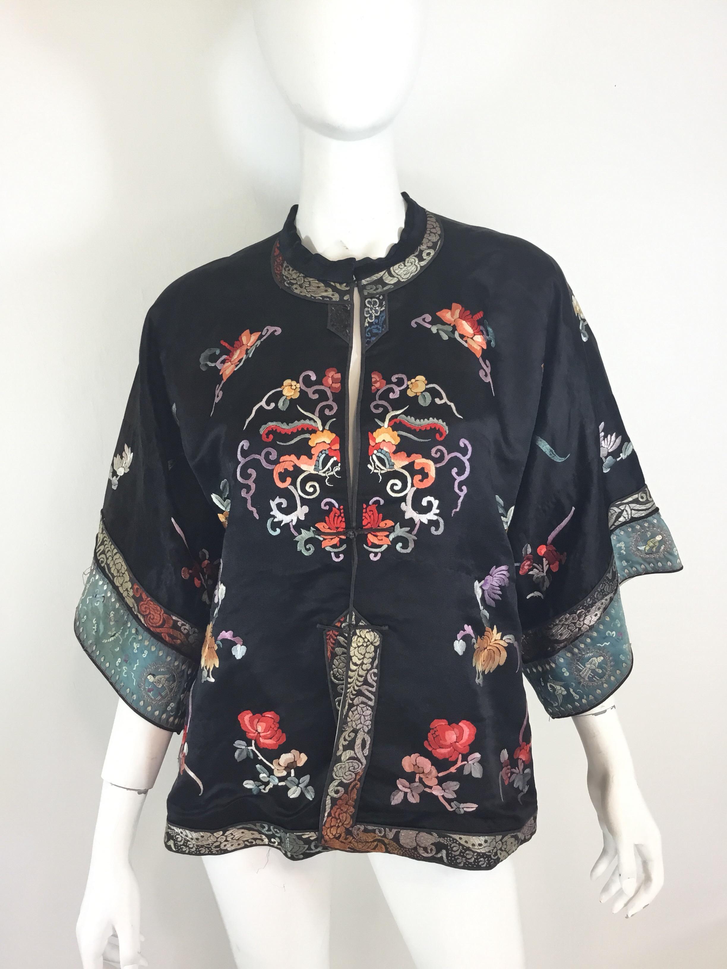 Chinese Silk Jacket, circa 1920 featured in black with multicolor embroidering throughout. Jacket has a hook and button fastenings. Measurements are as follows:

Bust 46”, sleeves 8.5” (dolman style sleeve), length 26”