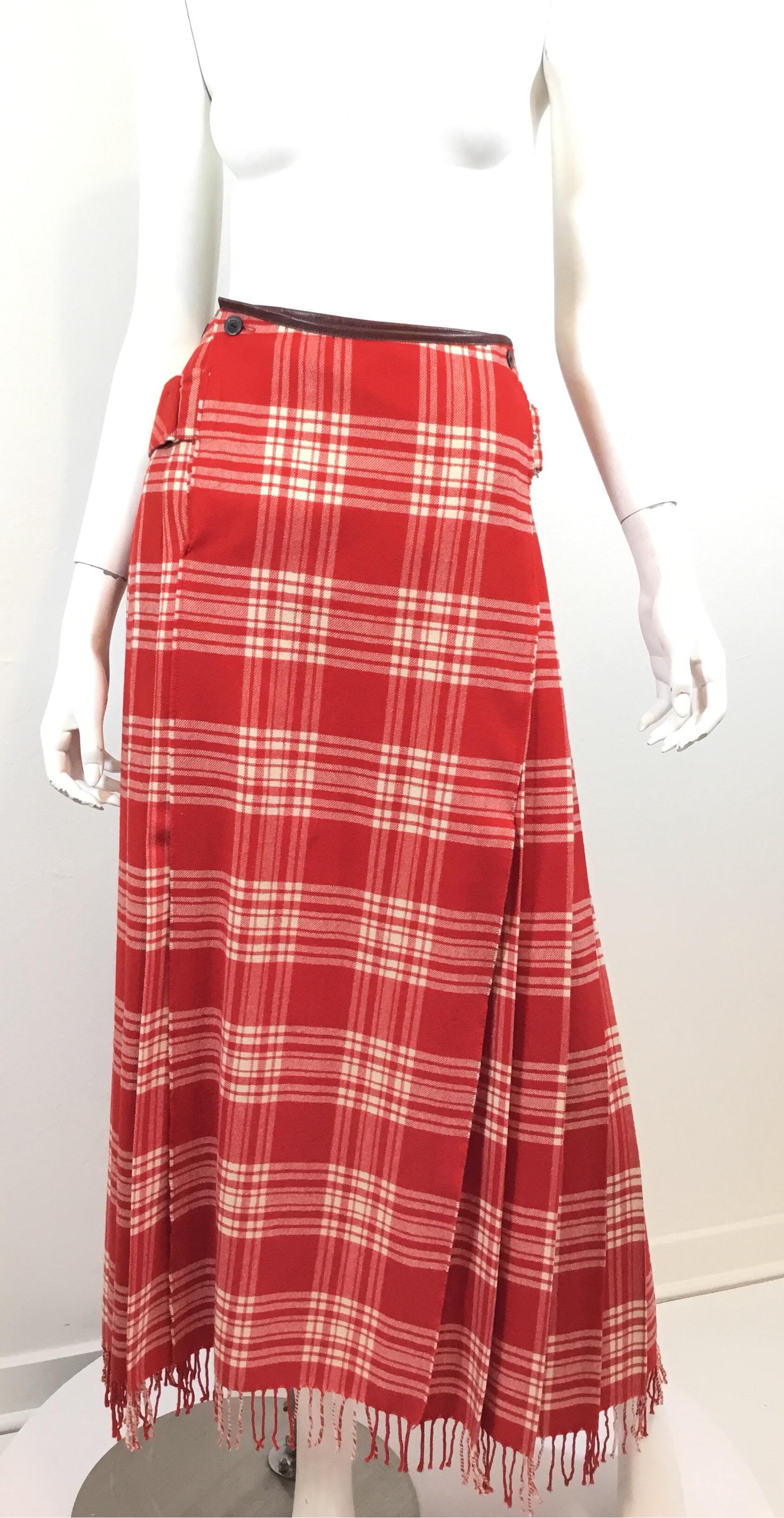 Vintage Jean Paul Gaultier kilt skirt featured in a red plaid with leather trimmings, button and belt fastening, and a fringed hem. Skirt is labeled a size 44 and composed of 100% wool. Made in Italy.

Waist 26”, hips 34”, length 39”