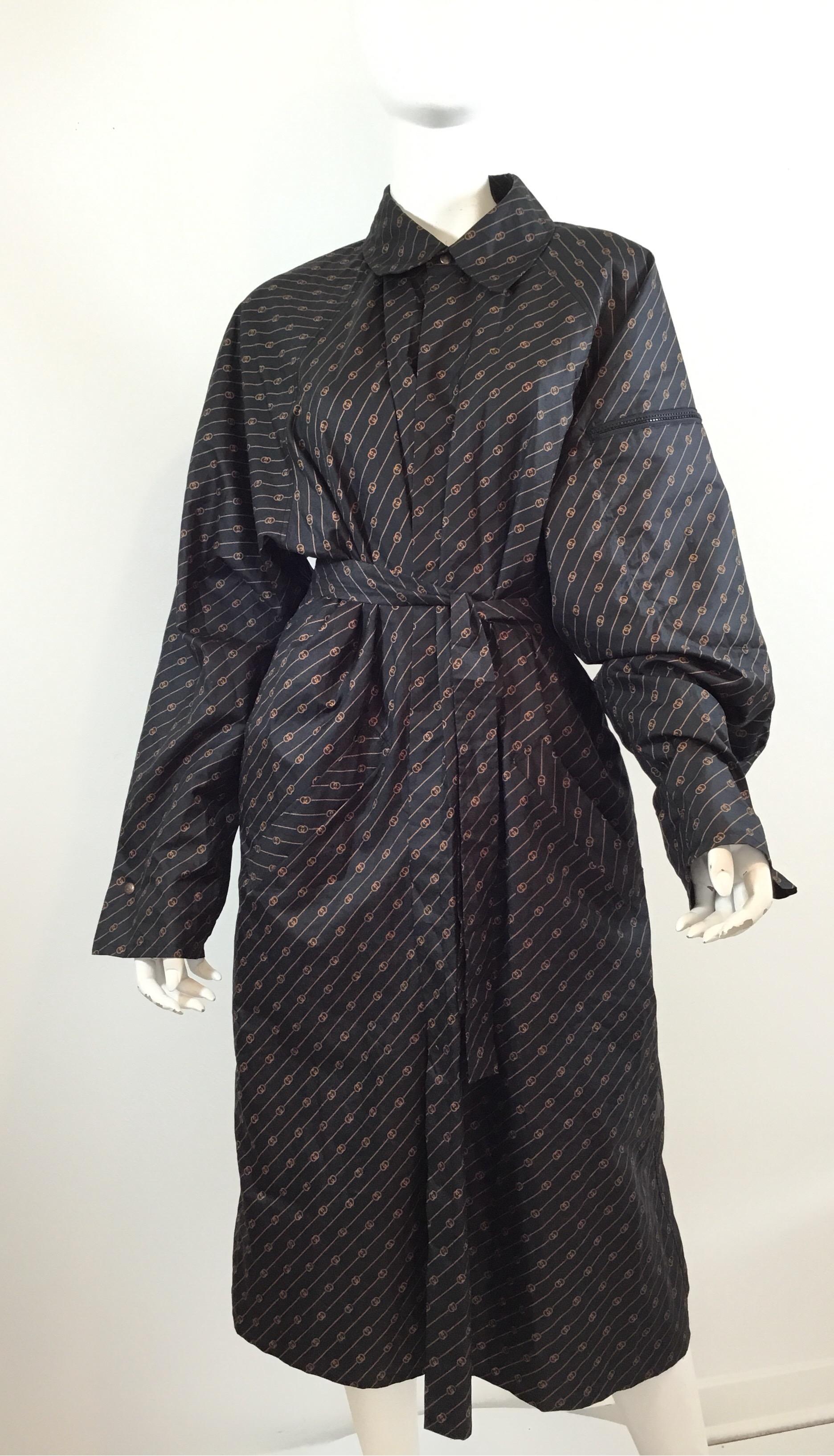 Vintage iconic Gucci raincoat with signature print throughout polyester material, made in Italy. Coat has a single snap button at the neck and a waist tie closure, pockets at the hips, pocket on the left sleeve in which also serves as the pocket to