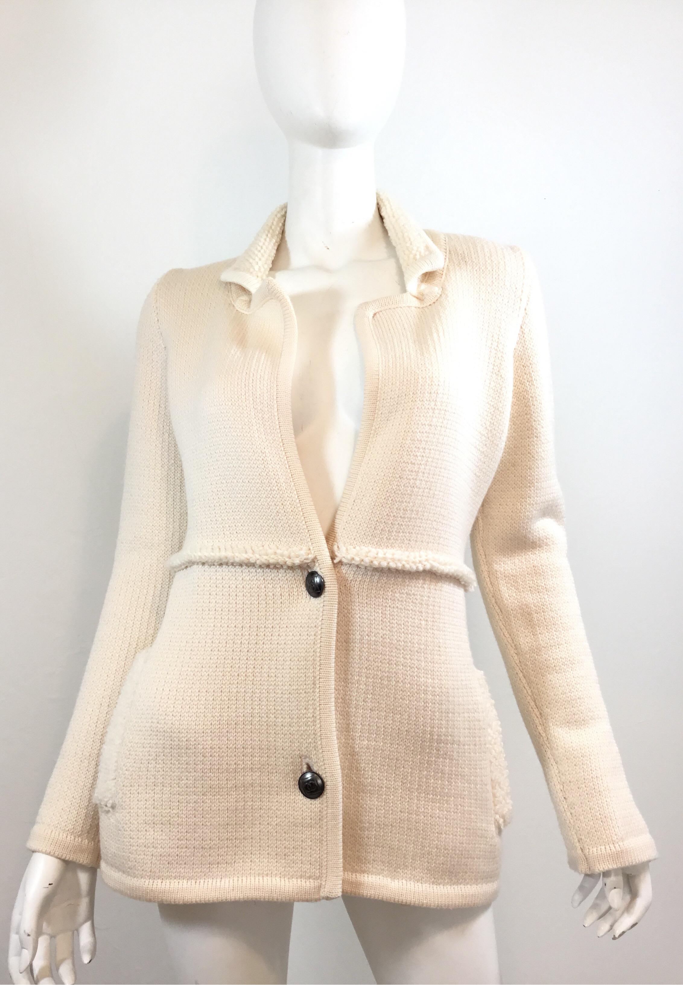 Chanel Identification sweater is featured in an ivory/Cream colored thick knit. Sweater has button fastenings and two pockets at the waist. Labeled Size 38, made in Italy, 100% Wool.

Bust 36”, sleeves 27”, shoulder to shoulder 14”, length 27”