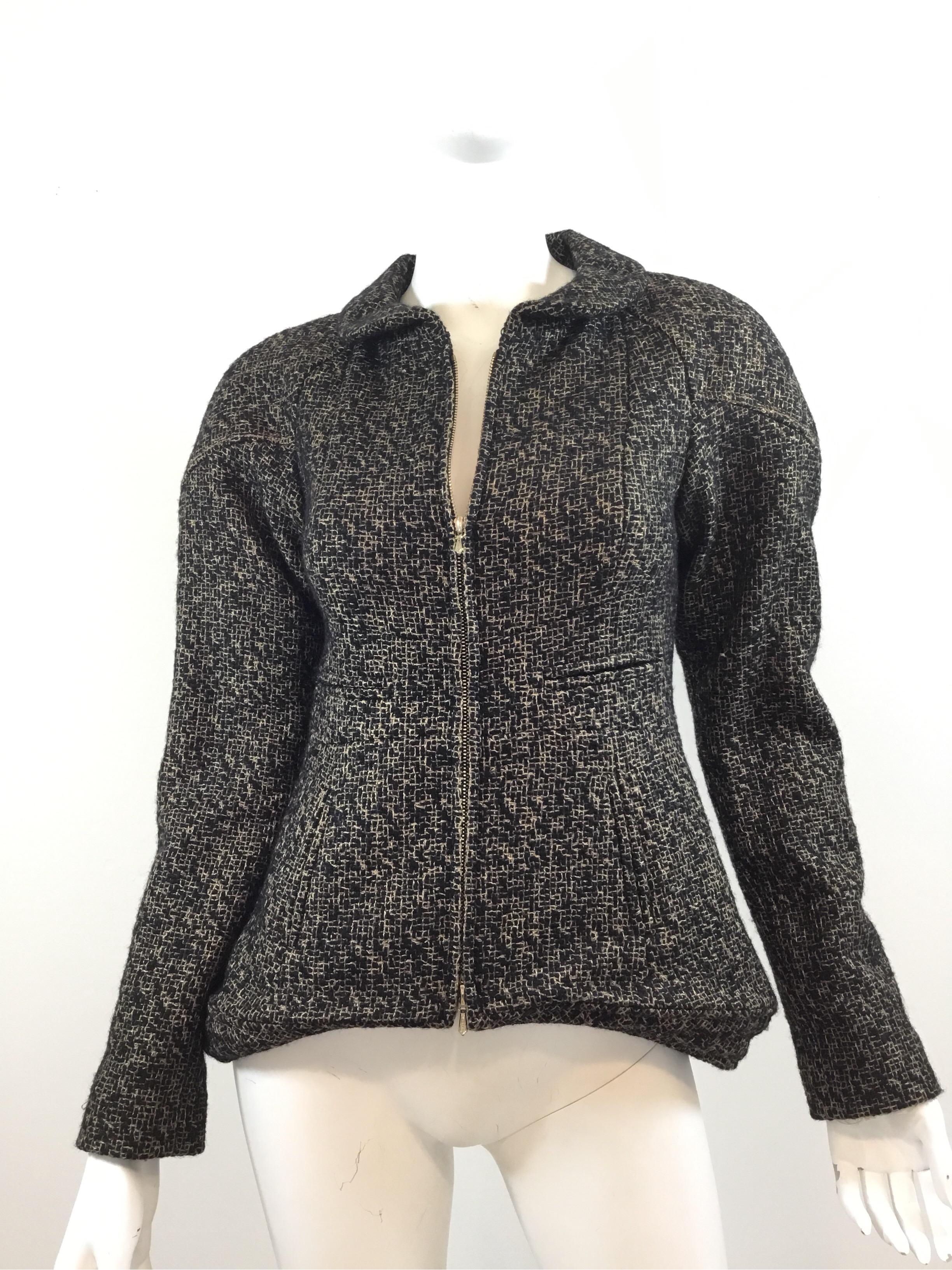Chanel zip up jacket is featured in a Black and gold colored Tweed knit, Peplum style waist, decorative slit pockets at the front, and goldtone Chanel buttons at the back. Jacket is fully lined in silk, labeled size 34. Made in France. 91% Wool, 9%