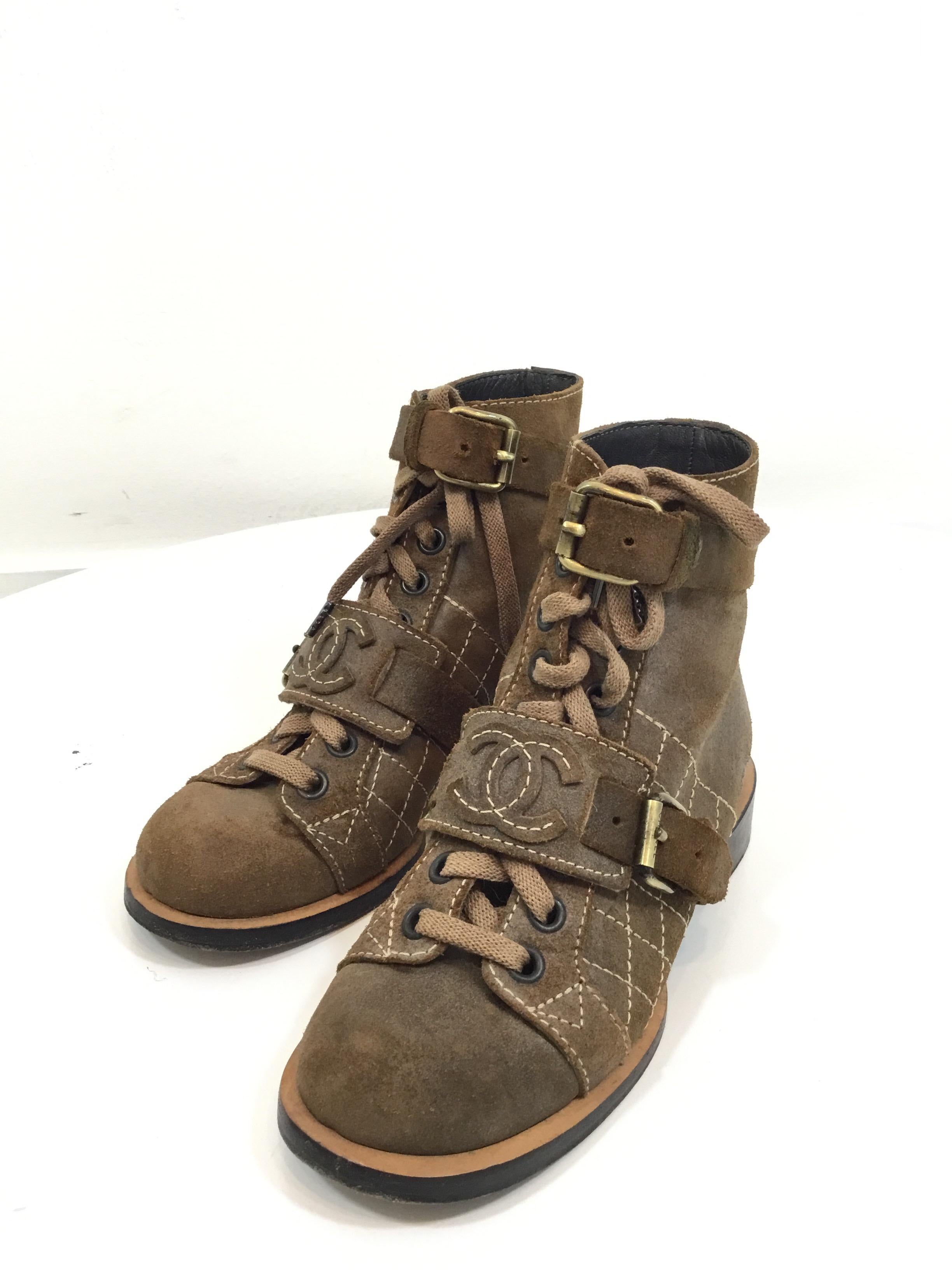 Chanel combat boots featured in a distressed brown suede leather with lace up fastening and a CC stitched buckle across the foot and ankle. Boots are a size 36, made in Italy. Shaft 5”, heel 1”, leather soles. Dust bags are included.