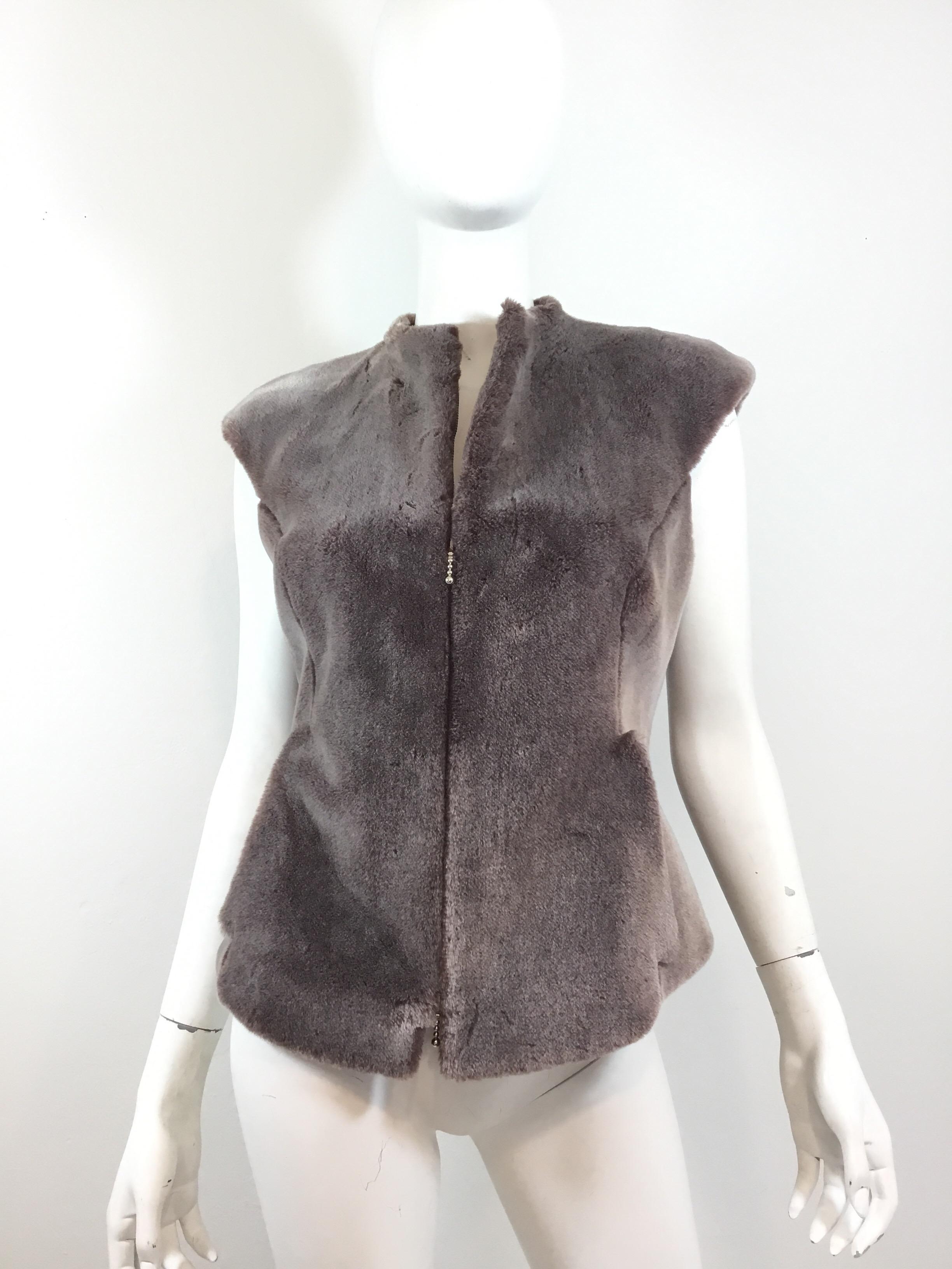 Chloé faux fur vest featured in a mauve-Grey color with a zippered fastening. Vest is fully lined and is a size 40. Composed of 73% acrylic and 27% cotton. Pockets at the waist have a leather trim lining. Made in France.

Bust 34”, length 25”