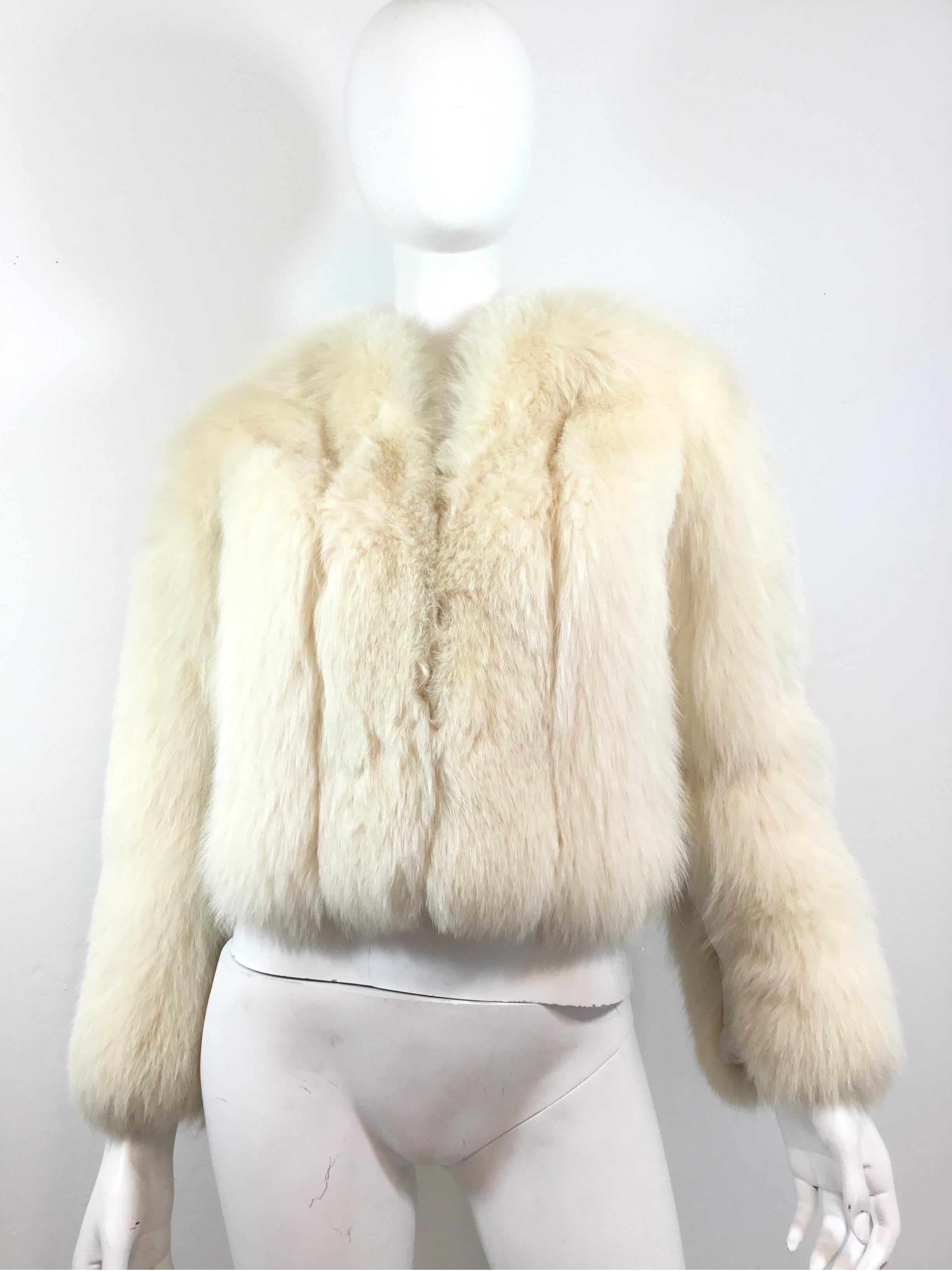 Sakowitz Vintage Fox fur chubby jacket featured in an ivory color with leather panels at the sides and under the sleeves. Hook closures along the front. Jacket has been fully re-lined and is in great vintage condition. Light wear to the leather