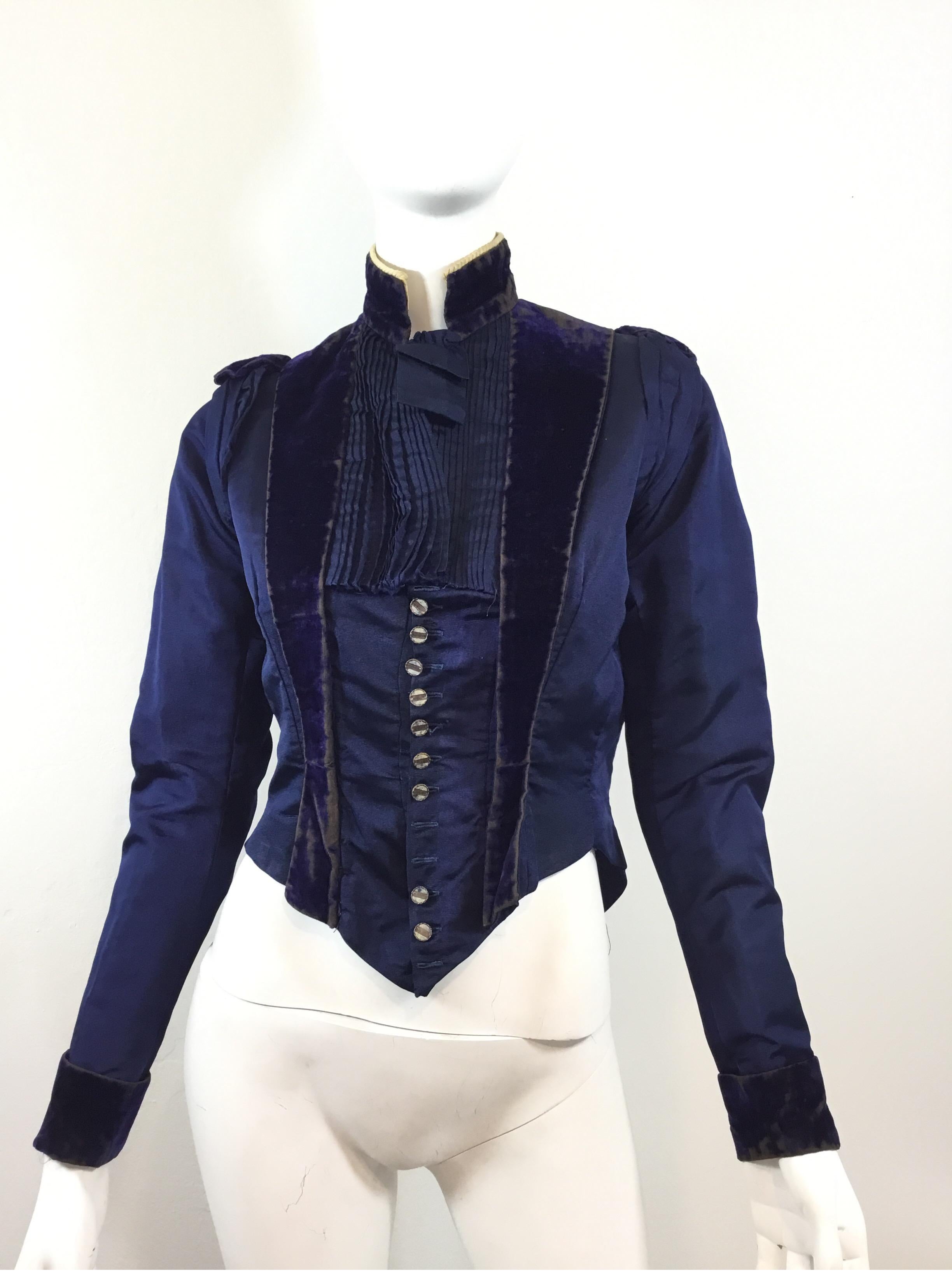 Victorian jacket featured in a navy with velvet panels, front button and hook-and-eye fastenings, a pintucked detail at the opening, and a Cream twisted piping along the collar. Jacket is boned at the bodice and fully lined; Lining shows some normal