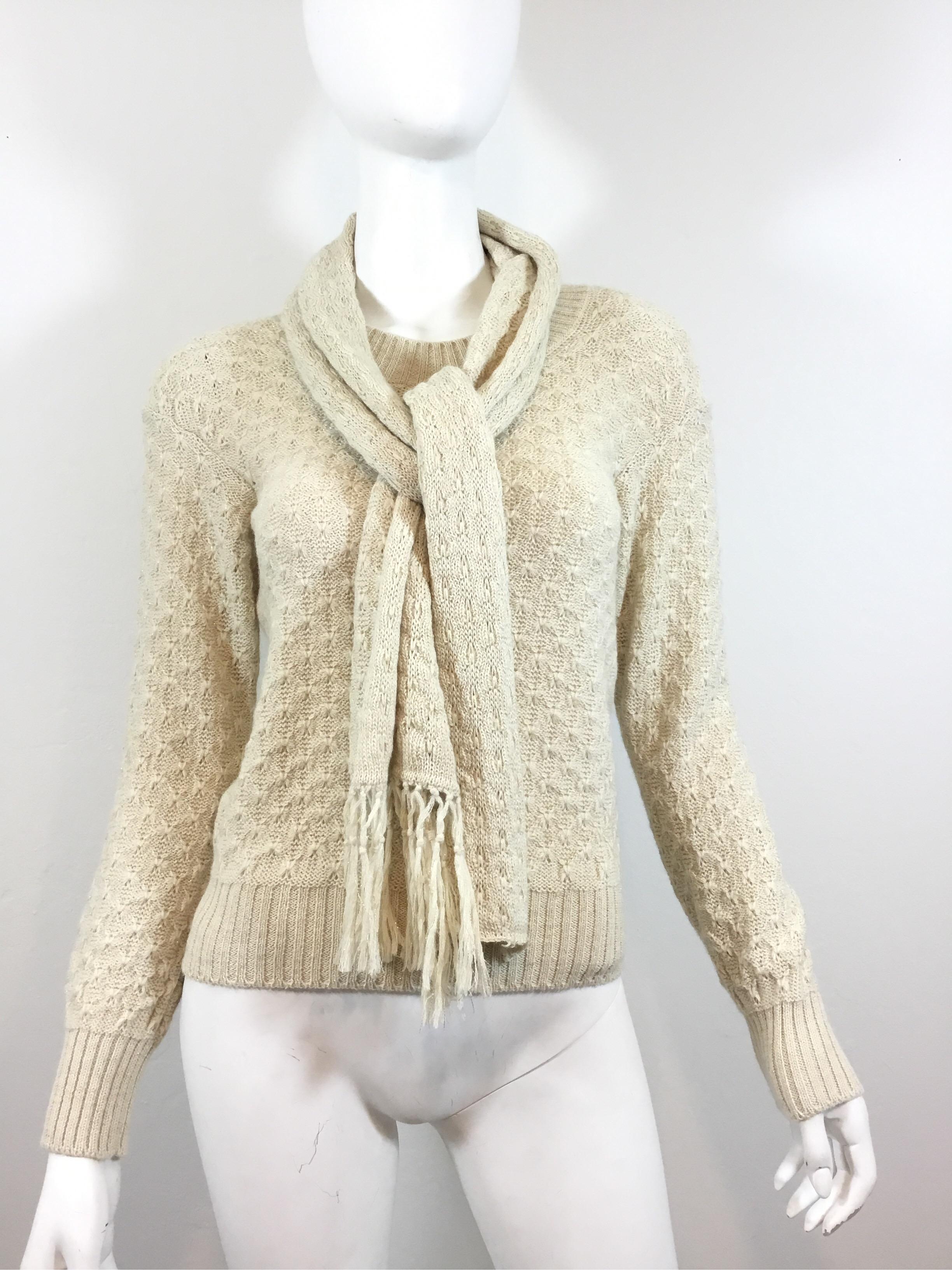 Chanel metallic cream knit pullover sweater with scarf included. Sweater has ribbed hemming and a pullover entry. Labeled size 38, made in Italy, and composed with a blend of alpaca/rayon/polyester. 

Bust 33'' (with stretch), sleeves 22'', length
