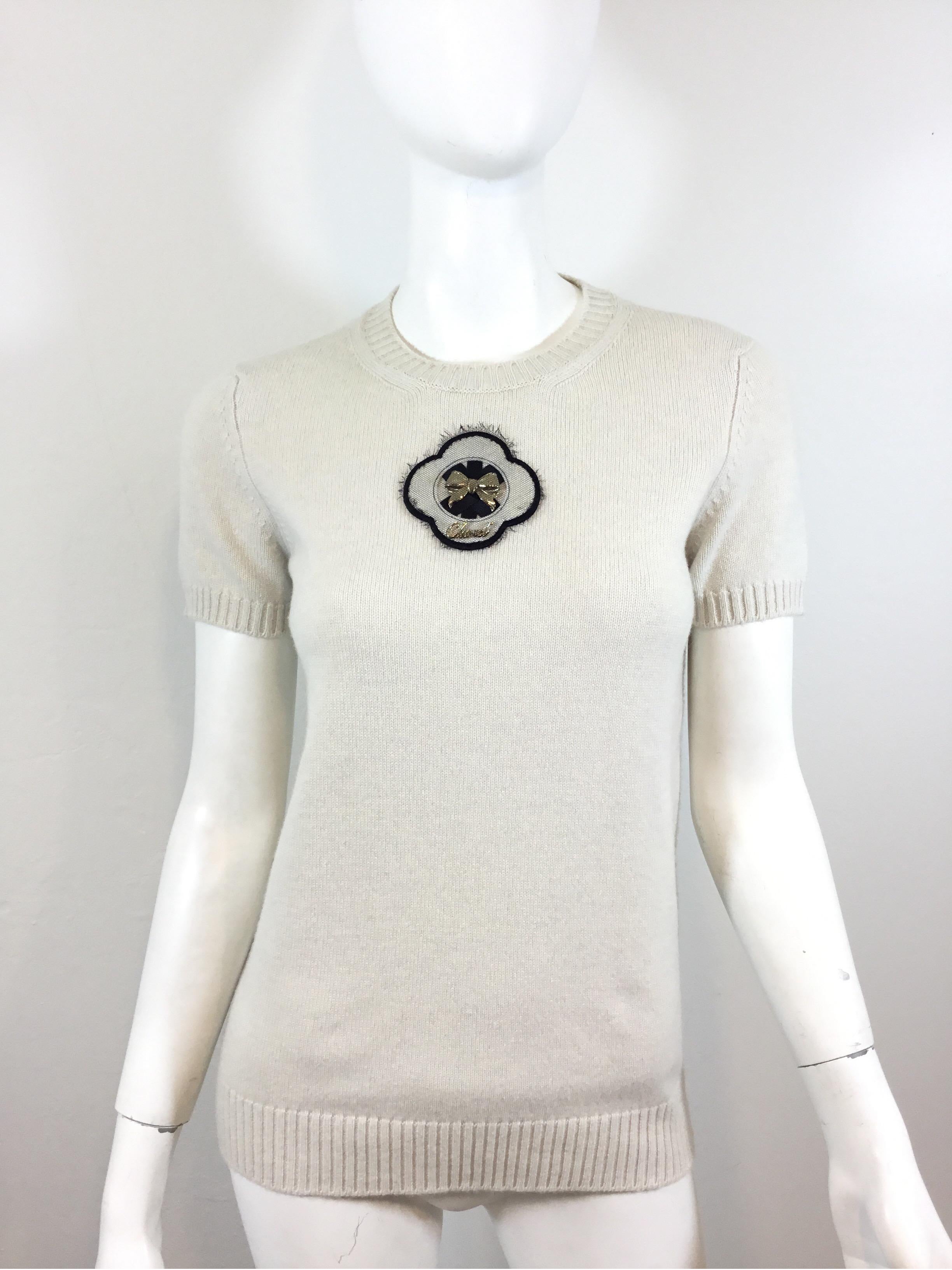 Chanel cashmere sweater top featured in a light grey color, 100% cashmere with a fringed mesh and metal applique at the front center. Sweater is new with tags, retailing at $1945, labeled size 38, from 2009 Fall collection, made in