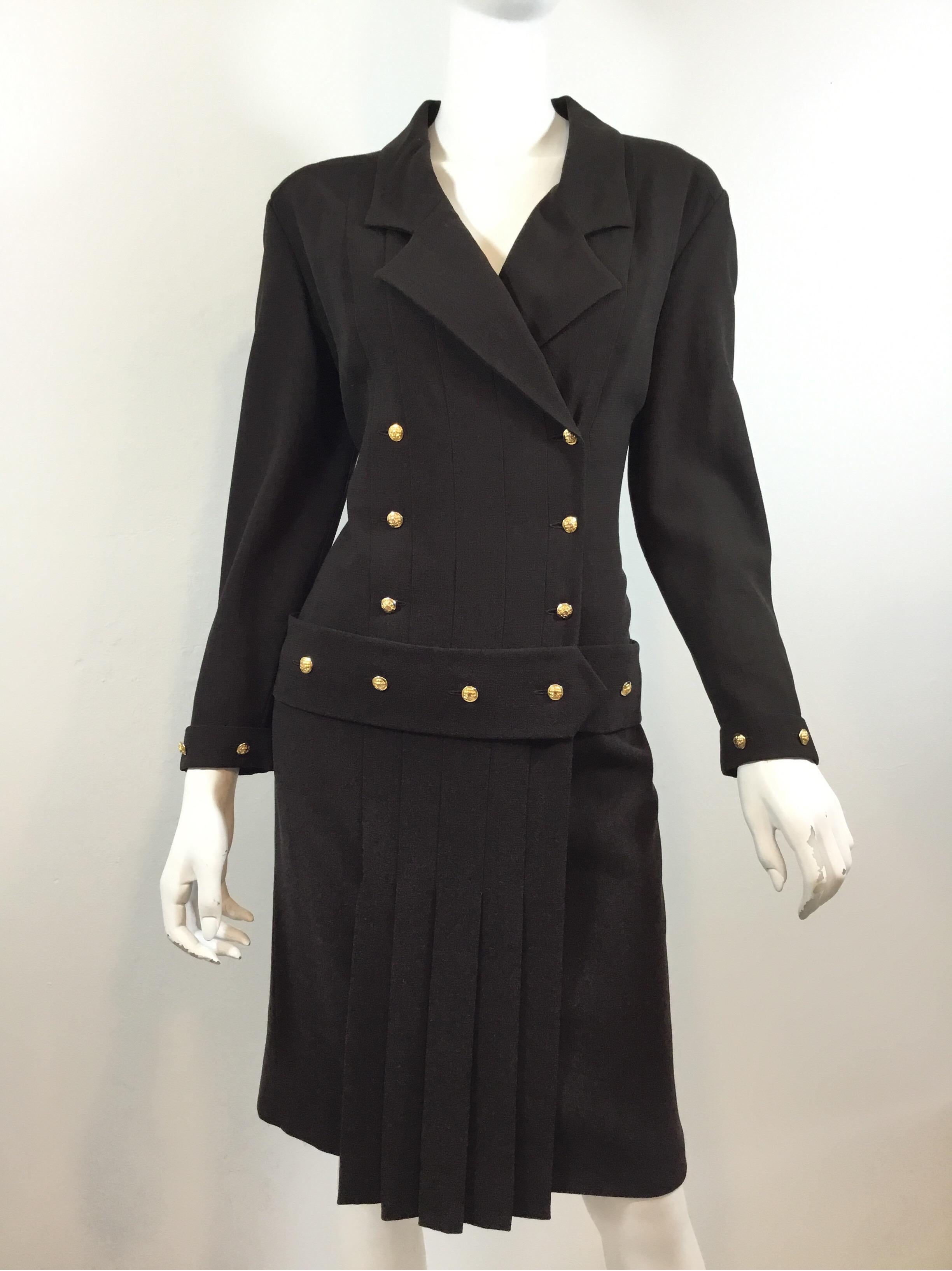 Chanel Vintage Dress featured in a brown crepe-like fabric with goldtone button closures that have a quilted detail and signature “CC” insignia, and a pleated skirt. Dress is labeled a size 44 and made in France.

Bust 42”, sleeves 22”, waist 36”,