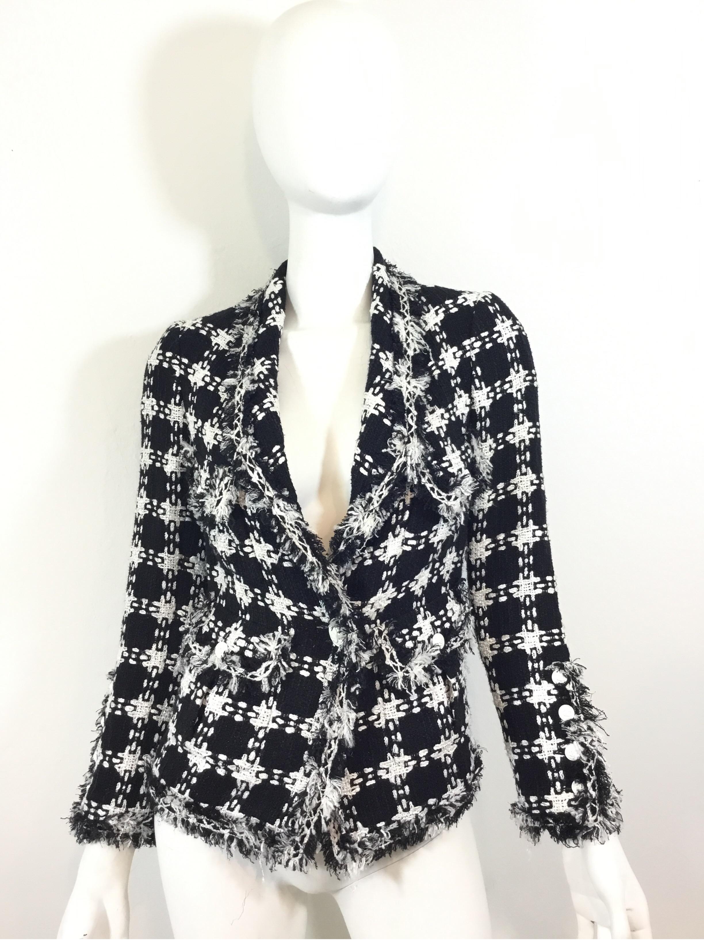 Chanel jacket in black and white tweed with fringed trimming throughout, White Quilted button closures, and four patch pockets with identical white buttons. Jacket is fully lined and has a chain trim along the hem. Size 34, made in France.

Bust