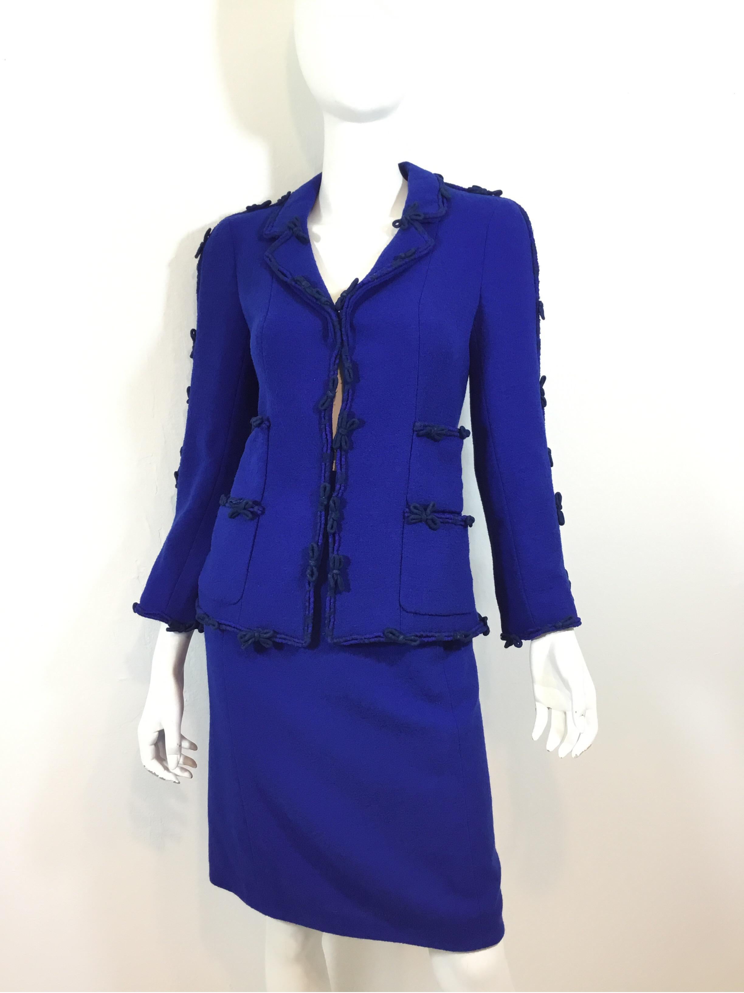 Chanel skirt suit featured in a royal blue tweed knit. Jacket has hook-and-eye fastenings, bow detail, four functional patch pockets, and a fully lining with a chain trim along the hem. Skirt has a back zipper and button closure, full lining and two