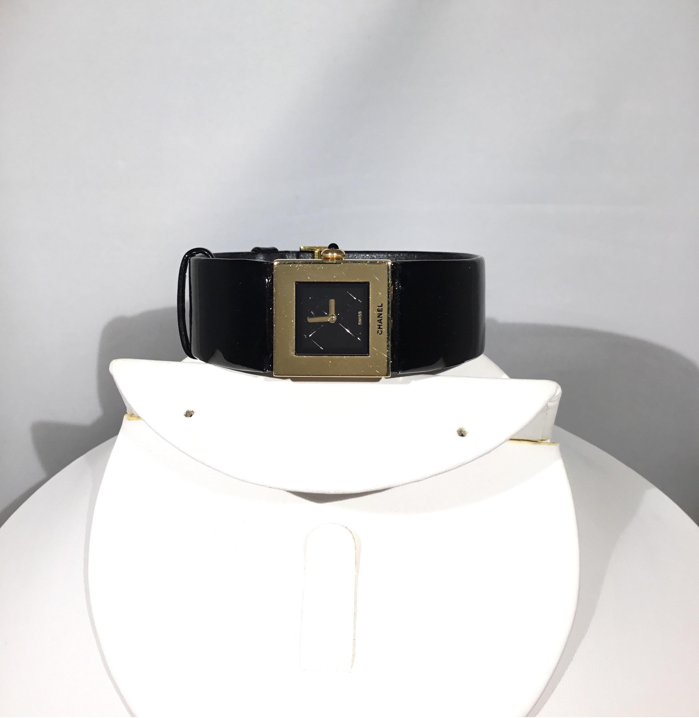 Chanel Matelassé watch in solid 18 K gold with a black patent leather adjustable band, Black quilted quartz dial. crown set with a black sapphire cabochon. Black patent leather bracelet (shows signs of use on the back), folding clasp in gold signed
