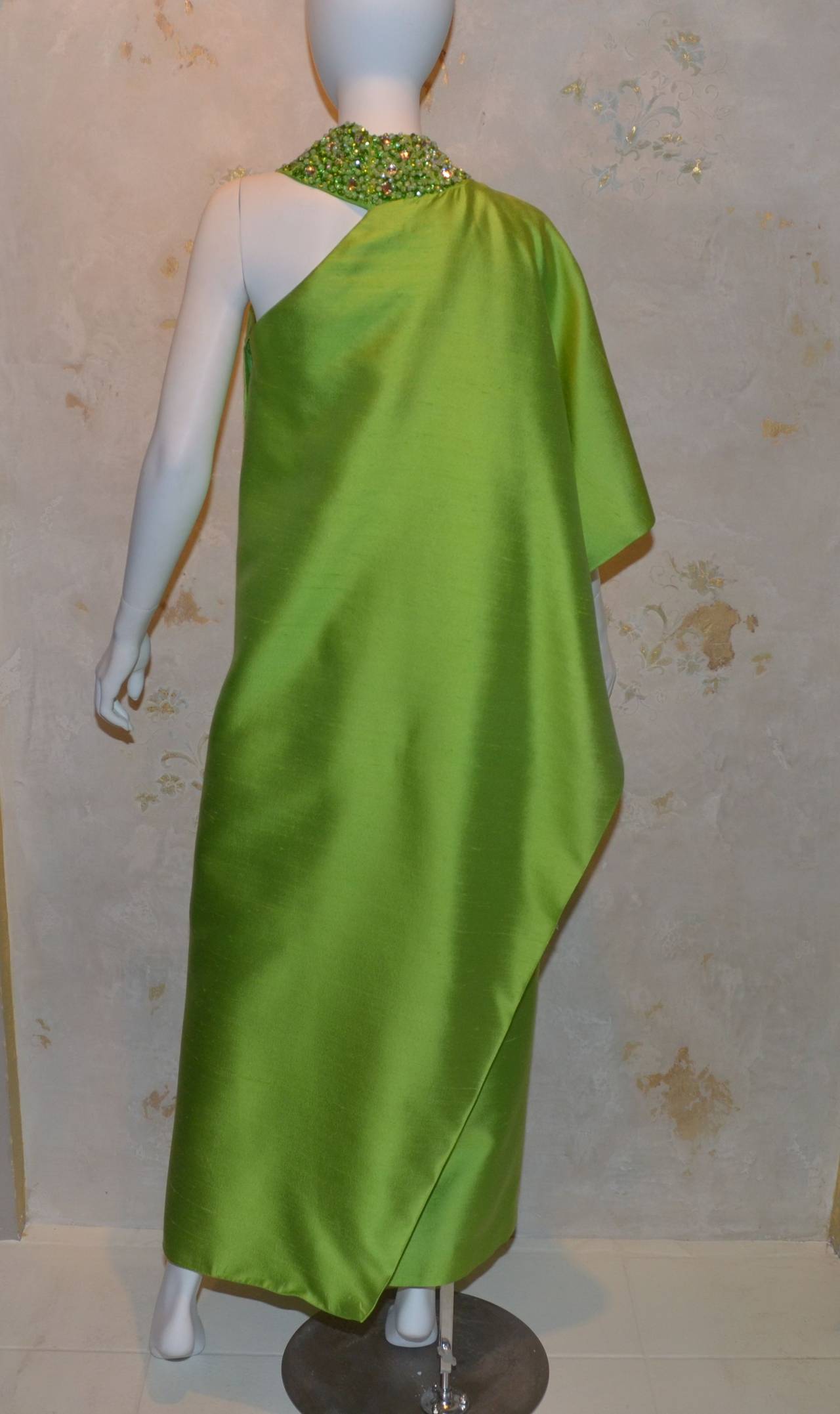 1960s Clifton Wilhide Silk Shantung One Shoulder Gown 
Lime Green structured silk shantung
Draped garment with column gown under and draped shoulder over.
Slit up center
Approximate size 4-6
Heavily beaded collar
2  layer garment with 2 hand