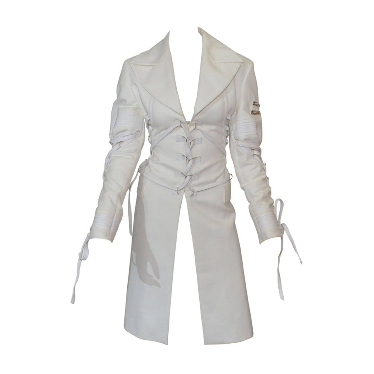 White Versace coat features a Corset style leather laces at front, sleeve and back. Front hook-and-eye closures. There are silver-tone rivets along the front, back, and cuffs of the coat for the leather lace-up tie detail. Left sleeve offers 2 small