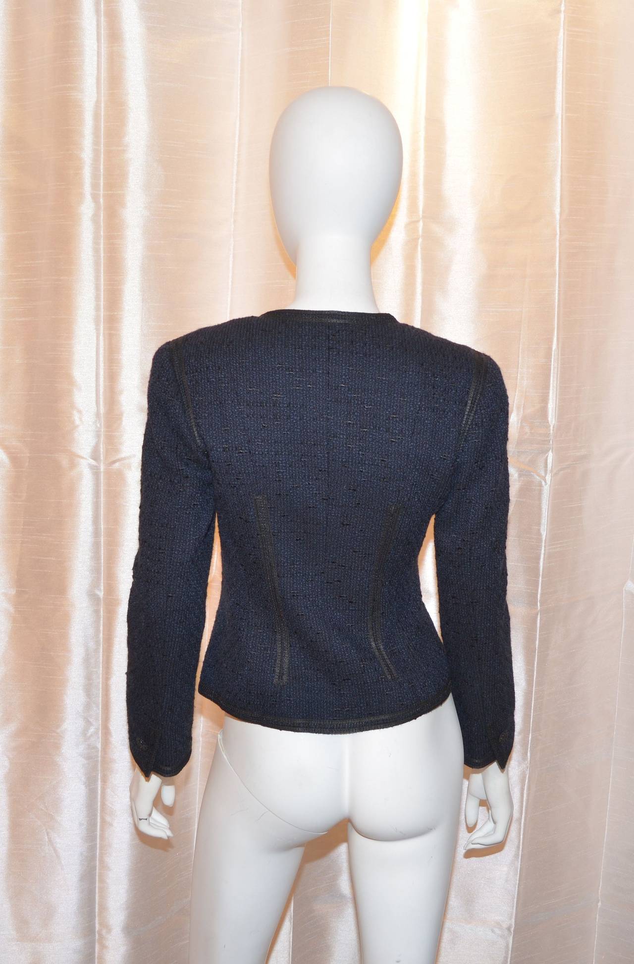 Chanel tweed blazer features an asymmetric collar, three rhinestone button closures along the front center and identical buttons on the cuffs. Blazer is fully lined with 95% silk and 5% spandex; made with 54% wool, 34% cotton, 11% rayon, and 1%