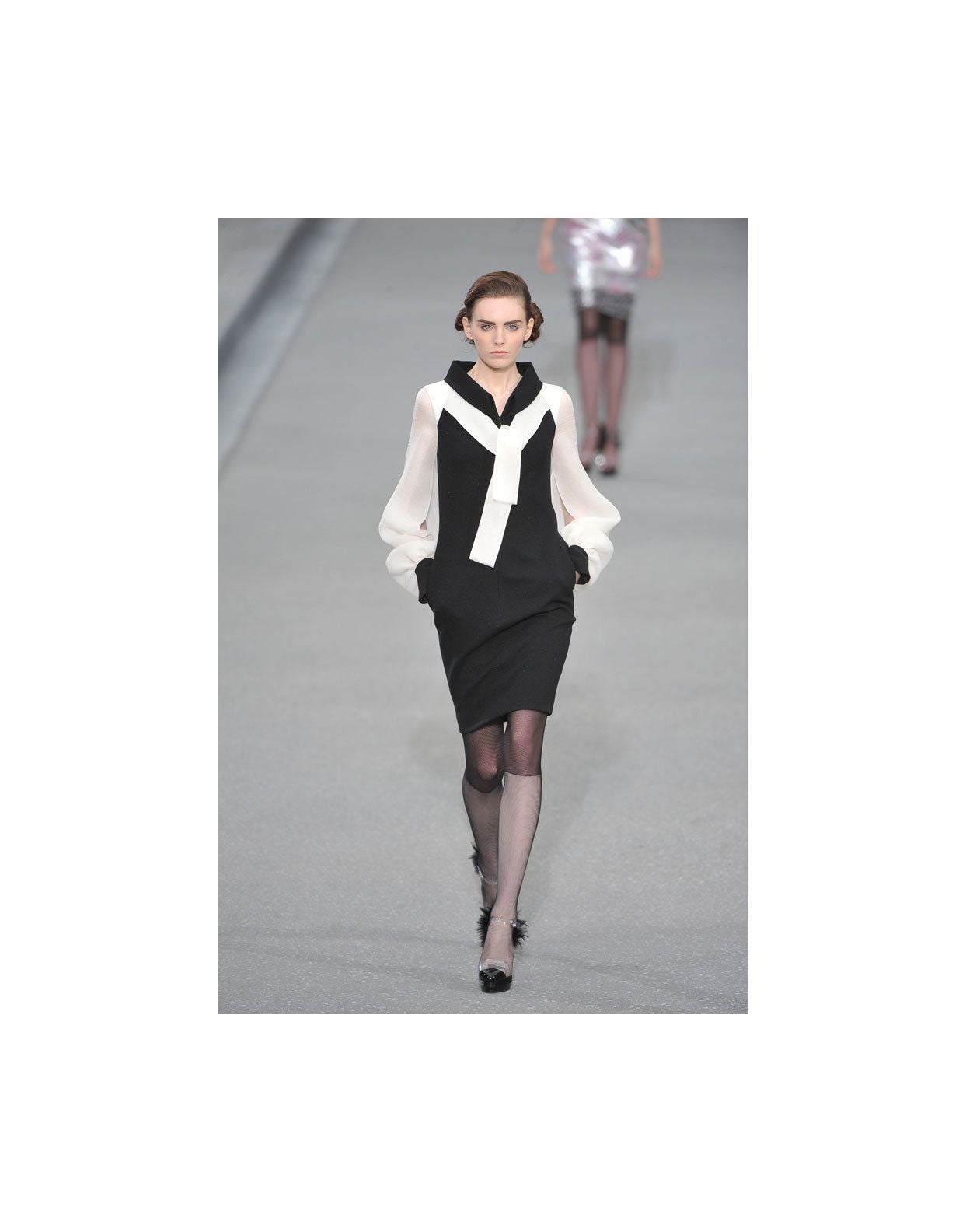 Chanel dress from spring 2009 RTW collection features a zipper front fastening and a hook-and-eye closure. Semi sheer ivory sleeves and bow tie detail, black cotton blend fabric has some shimmer to it. Sleeves have button closures at the cuffs.