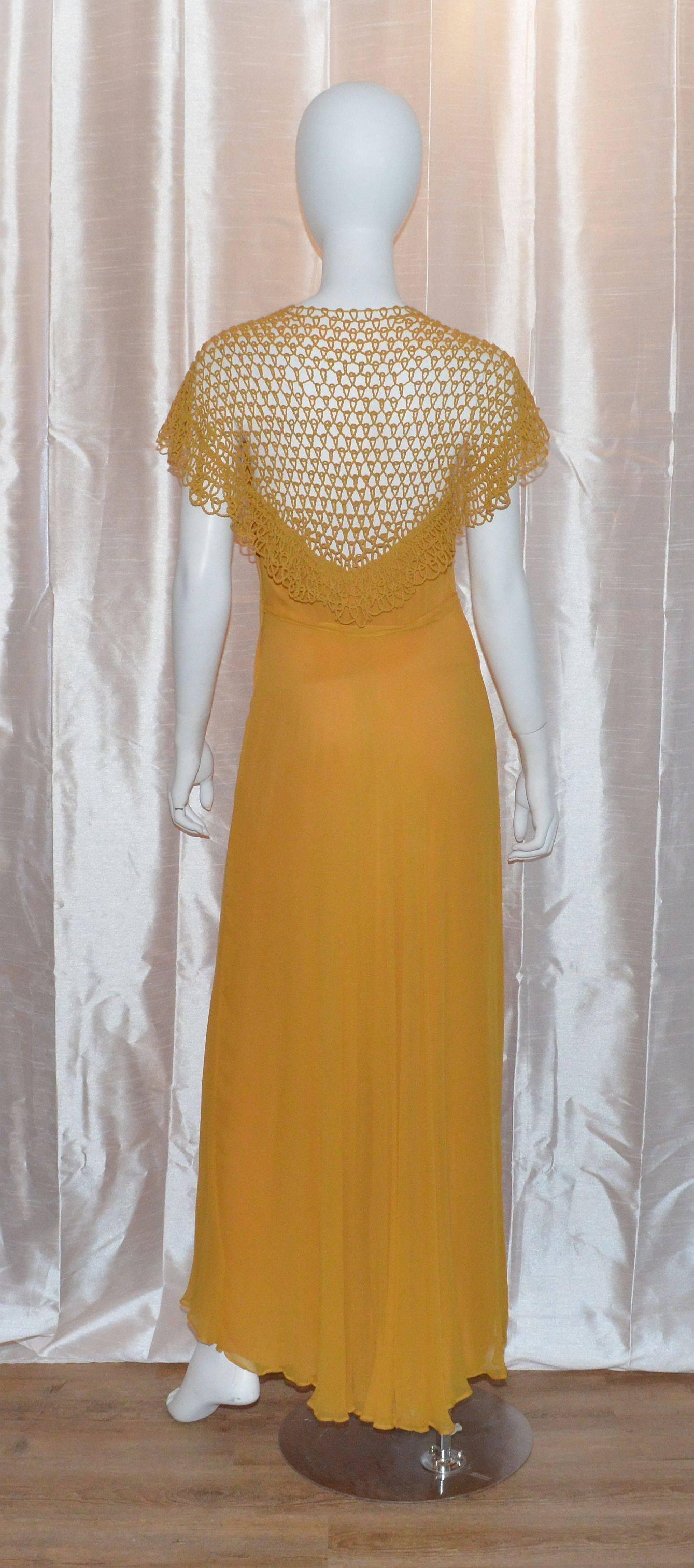 Vintage 1930's gown features a beautiful crochet neckline that continues along the back. Dress is fully lined and has a metal side zipper closure. 

Measurements:
Bust - 32''
Waist - 26''
Hips - 39''
Length - 59''