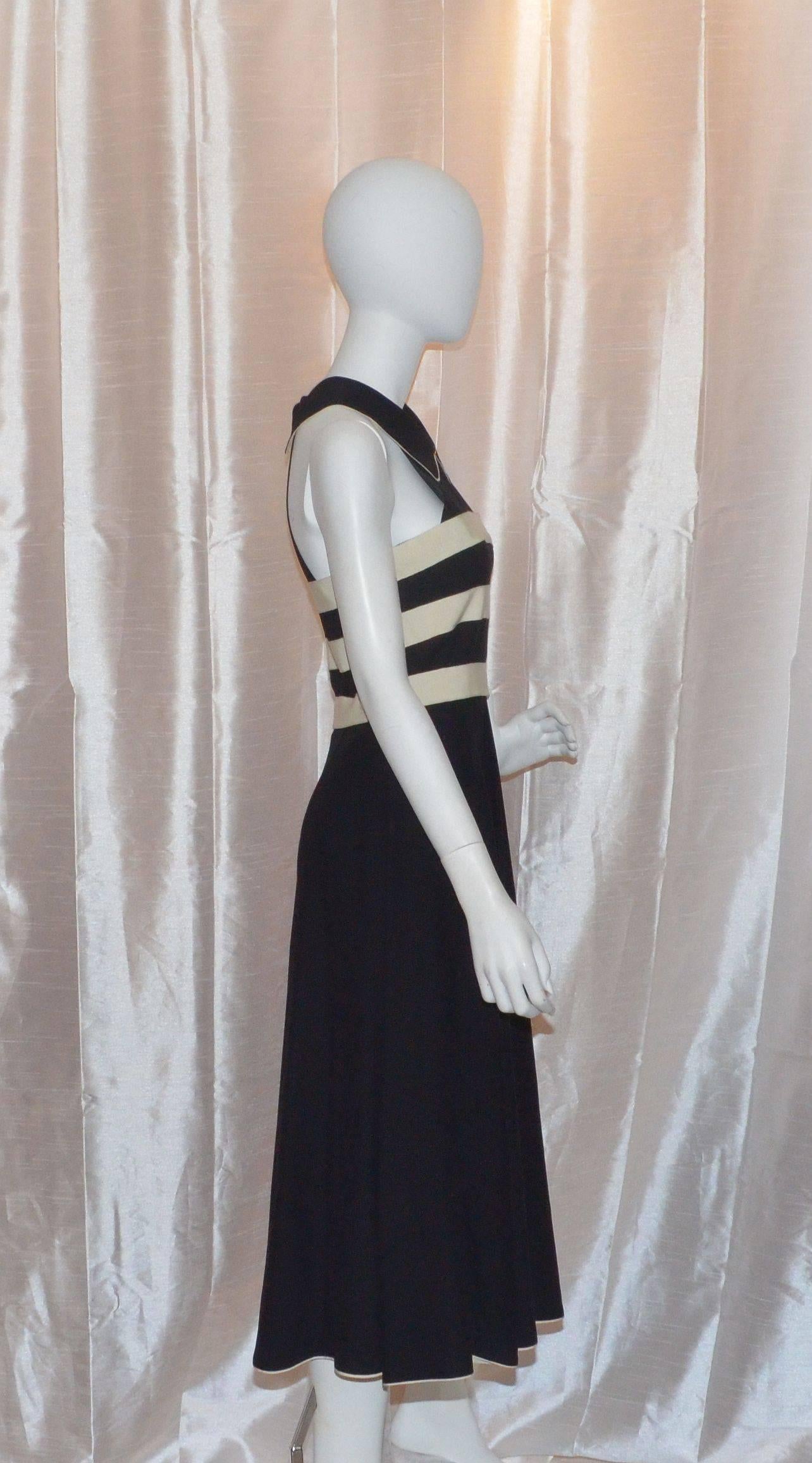 Black crepe Chanel dress features a key-hole detail neckline with decorative 'CC' button closure, back zipper closure with buttons at the collars. Ivory faille ribbon trim at the bandeau bodice, pointed collar and hem. Black and ivory striped