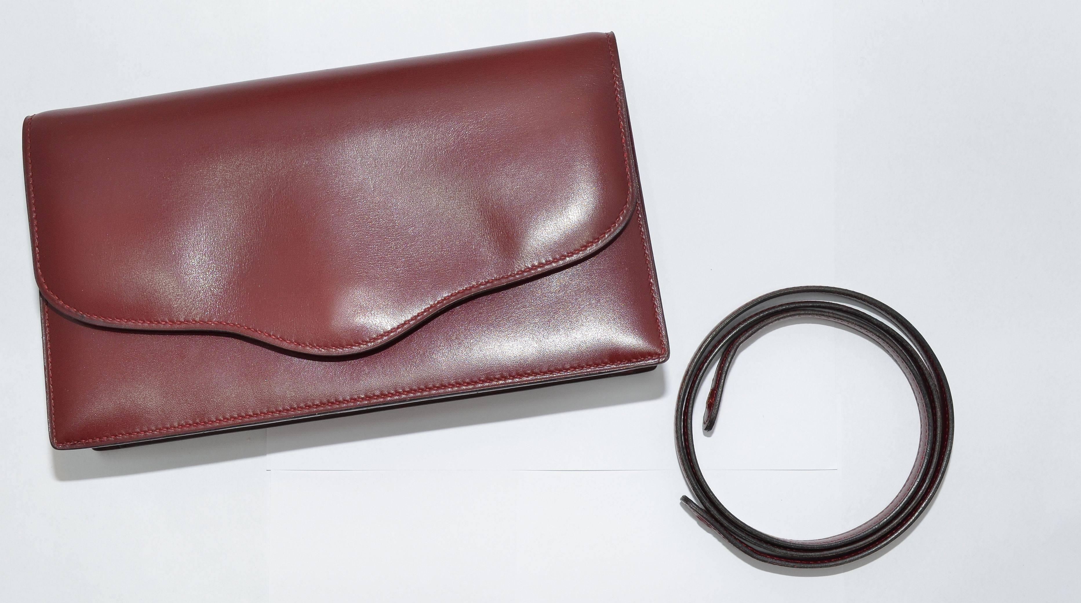Hermes 2 way clutch was the inspiration for the Constance. Clutch is featured in a deep burgundy box calf leather has a concealed snap closure, and a flat strap for optional ways to wear. Interior is fully lined in leather, one separate compartment,