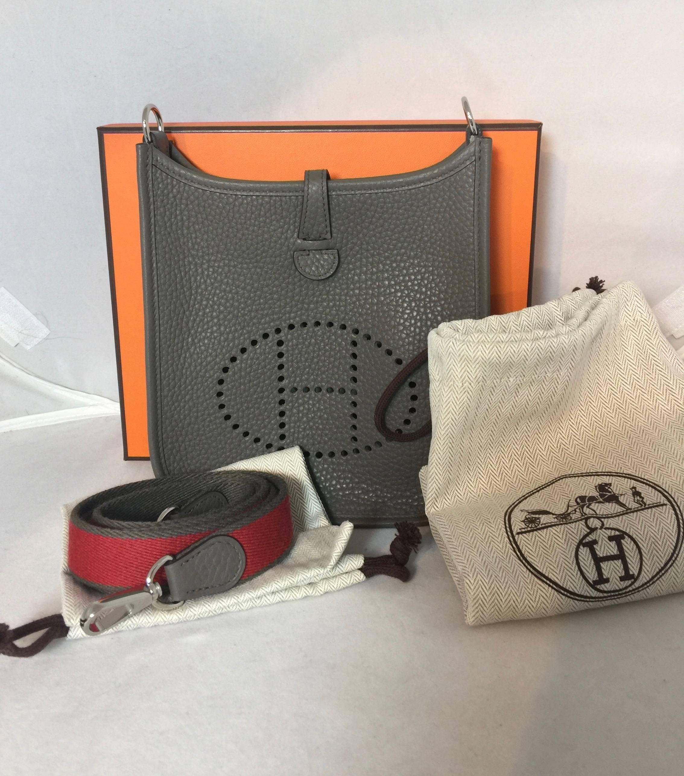 Brand new in box Hermes 2016 Etain Evelyne TPM in Clemence leather with removable 2 color grey/red strap. 

This bag in the new color Etain (gray) is waitlisted 8 months to 1 year and is extremely hard to get. 

Bag comes with original box, Bag,