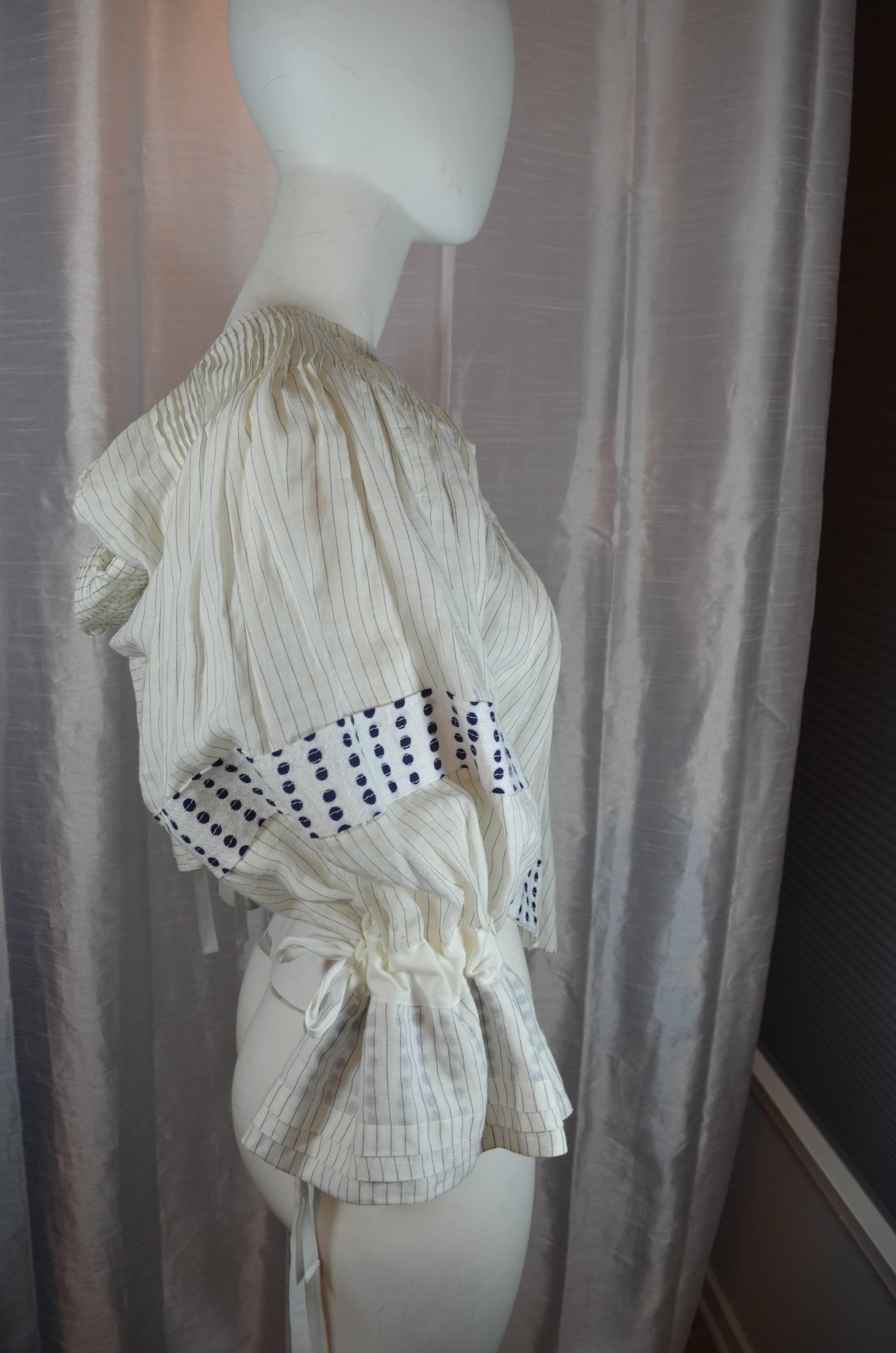 Tao Kurihara Comme des Garçons Blouse 2007

Cotton shirting material peasant blouse with striped and polka dot patterns in blue and white lightweight shirt fabric. Pleating throughout, unfinished hem, peasant sleeves with drawstring wrist ties.