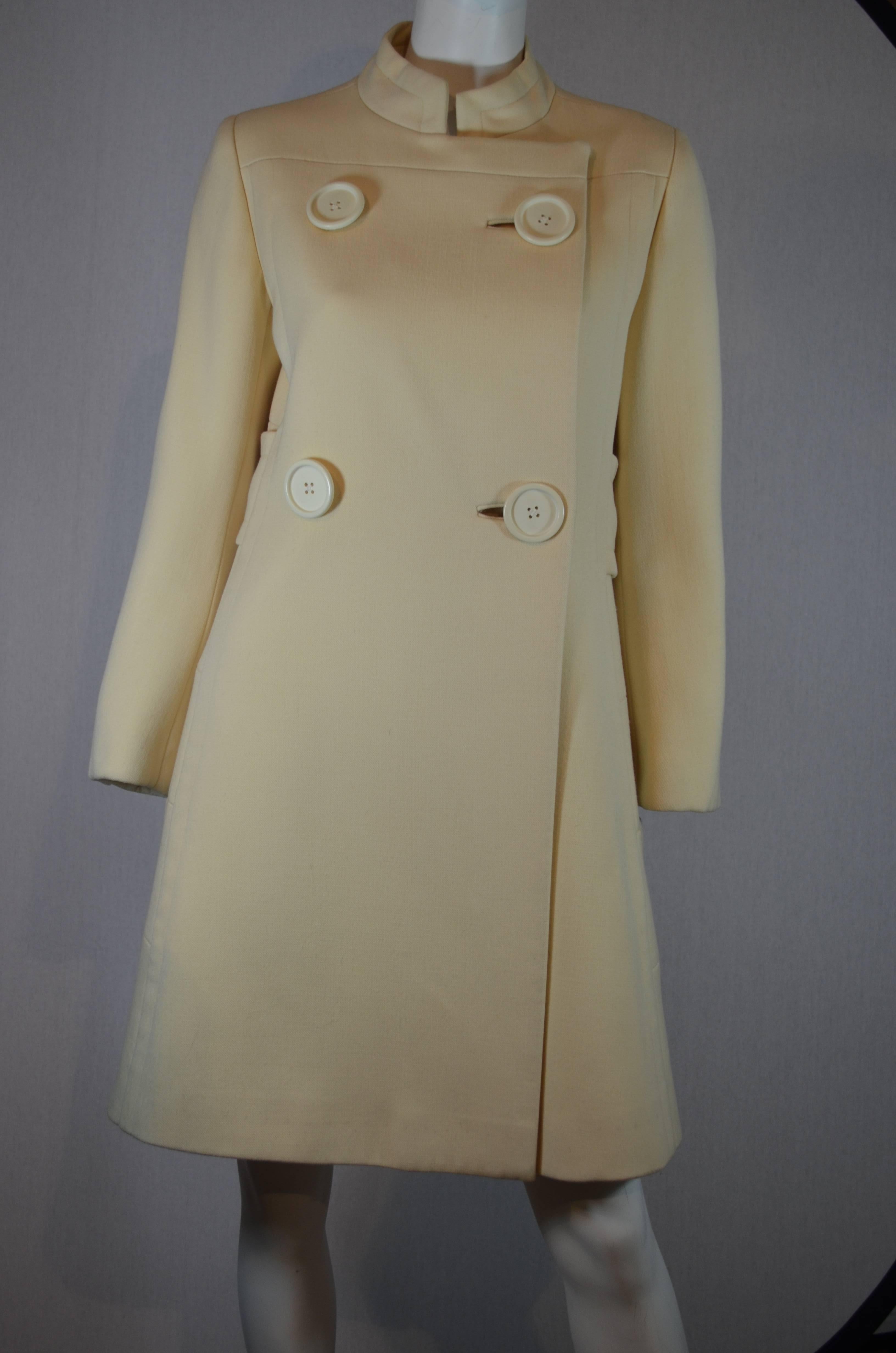 1960's cream structured wool ladies proper coat with welted seams.  4 huge buttons, double breasted, mandarin collar, fully lined.  It has a faux belted back.  It has two front pockets at hips and fully lined.  

Condition:  Excellent vintage