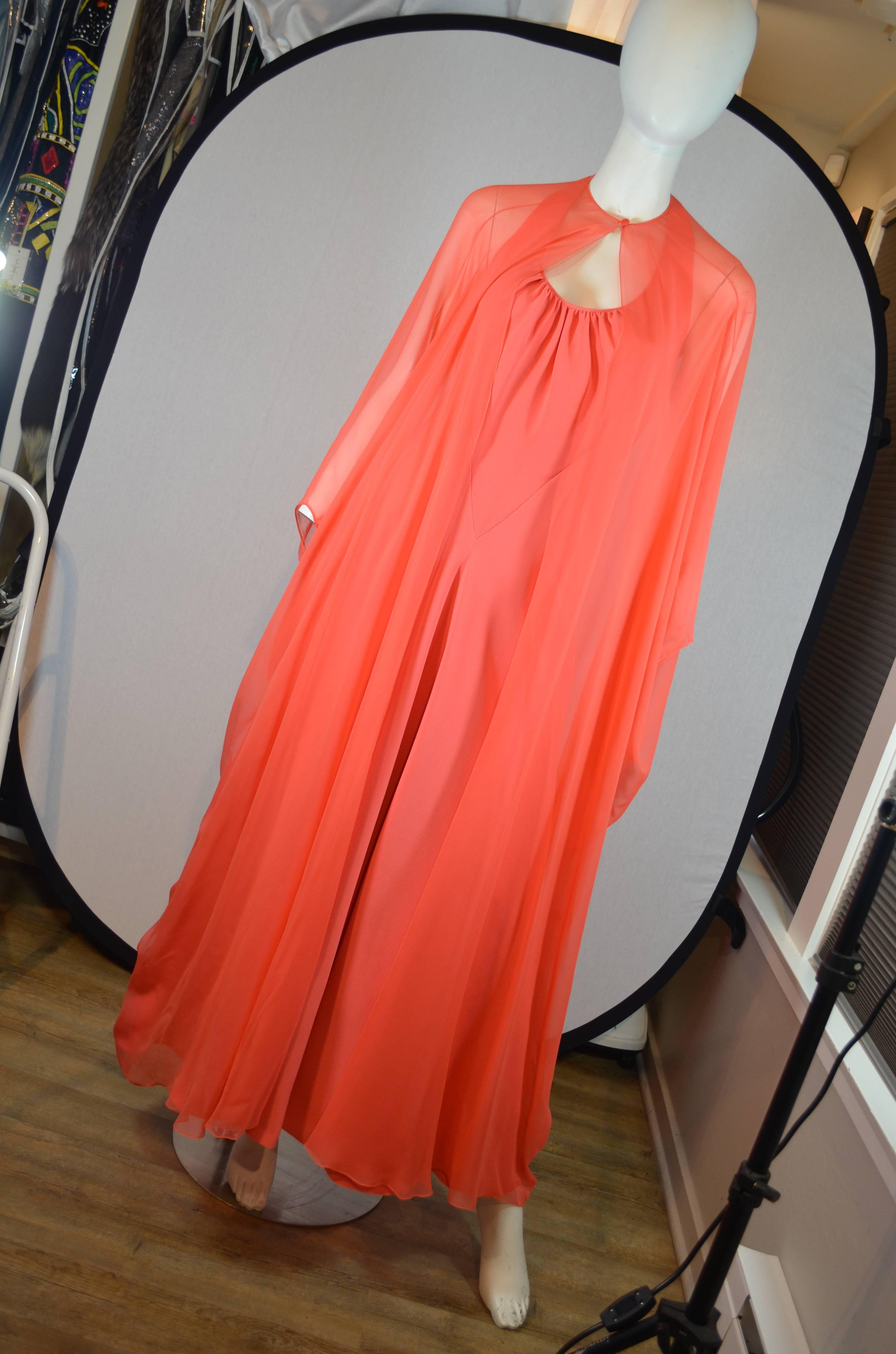 1970's Stavropoulos Coral Halter Gown With Silk Chiffon Cape
Coral gown featuring a bias cut halter crepe gown with light gathering at chest and v shaped style lines in the front to place the fabric on the bias. Sheer coral silk chiffon cape