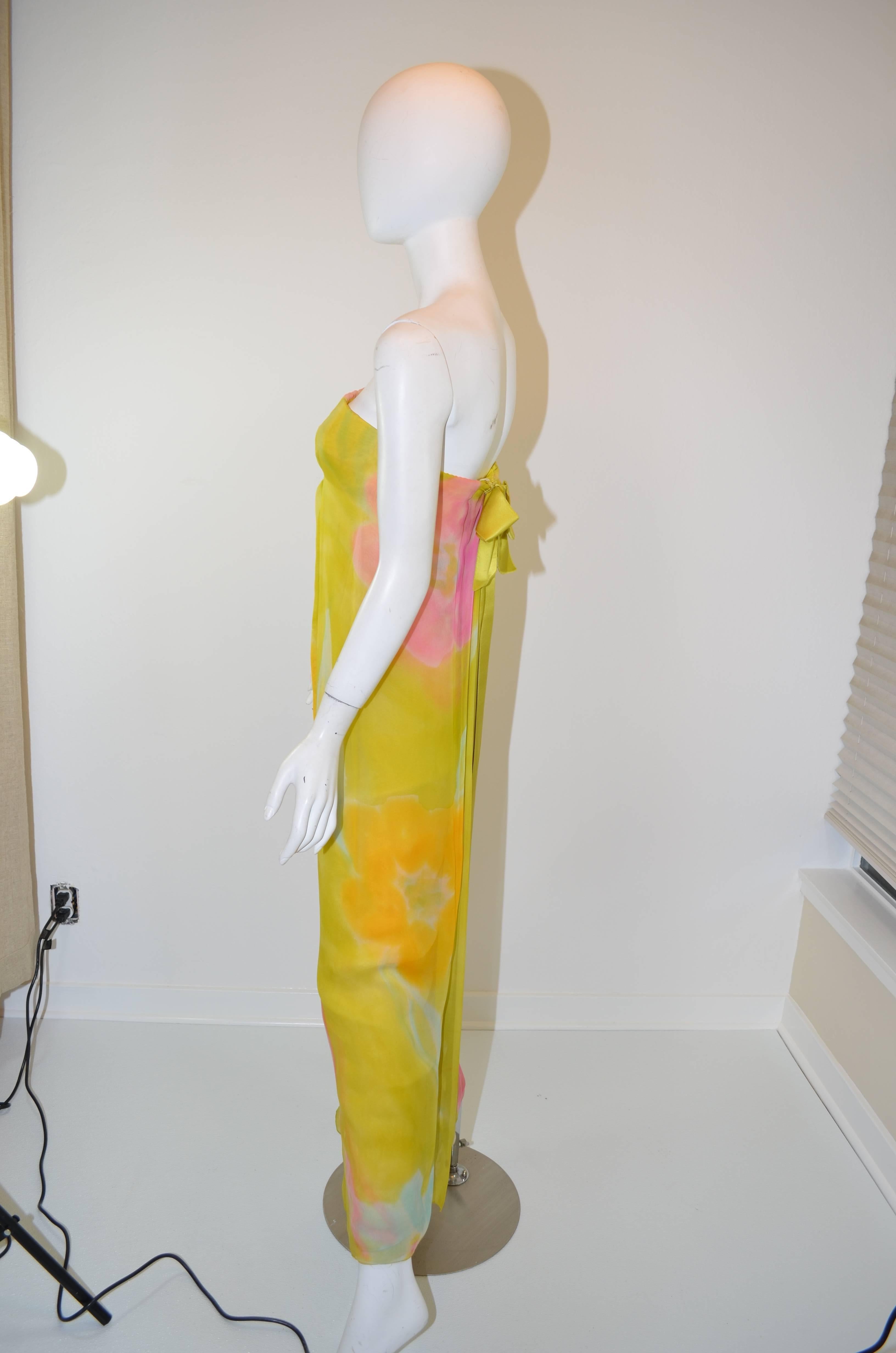 Beautiful vintage 1960's Sarmi chiffon strapless evening gown. Featuring yellow, green, and pink chiffon floral pattern, with a satin bow in the back that snaps closed over the back of the gown. Built in boned bodice holds the gown up. The bow's