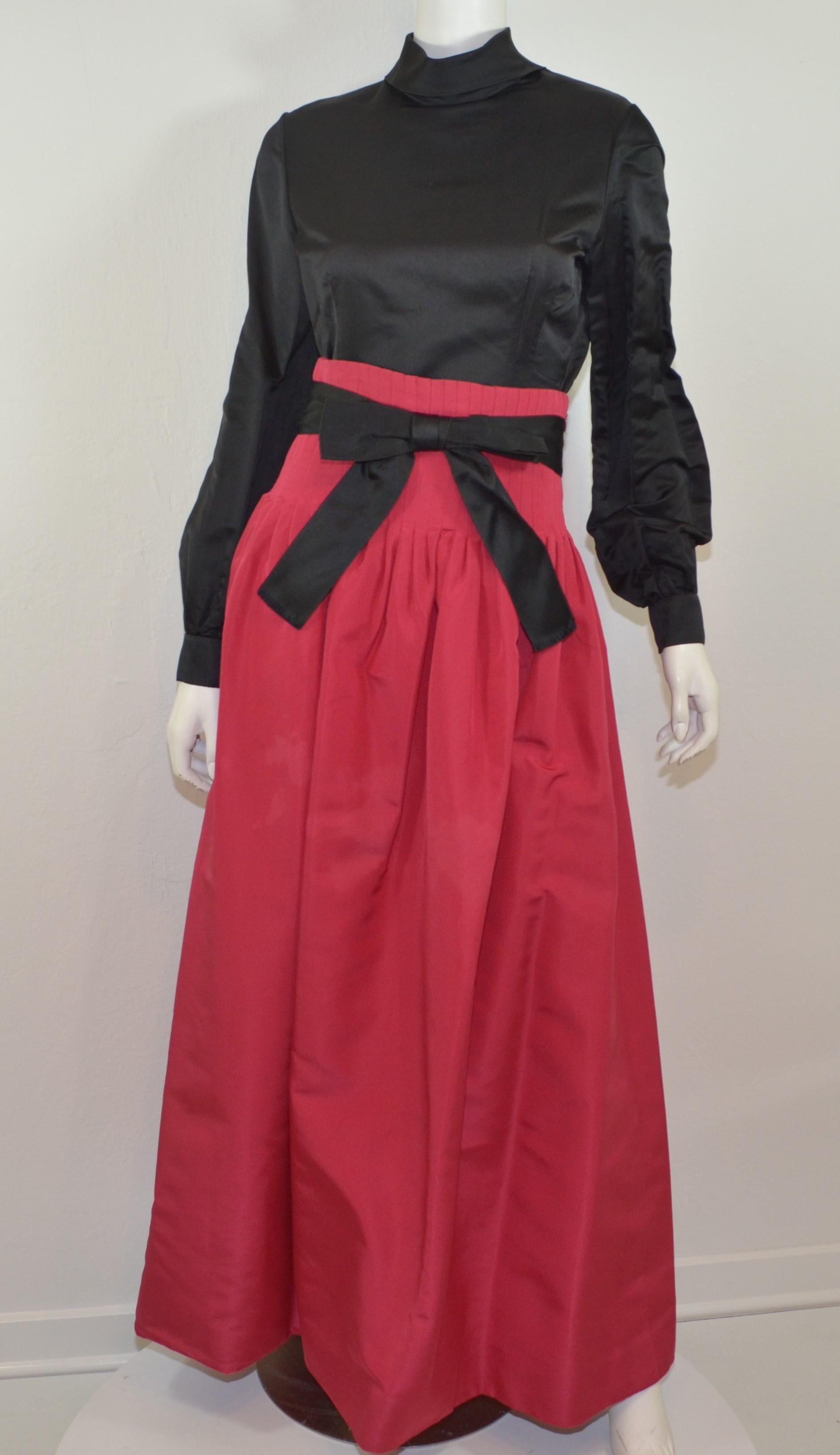 Pierre Cardin Mid-Century Modern full skirt and top ensemble. Skirt is a fuchsia color with a pintucked waistline, side zipper fastening and a black satin bow belt with snap and hook closures. Black satin top has a mock neck design, snap buttons at
