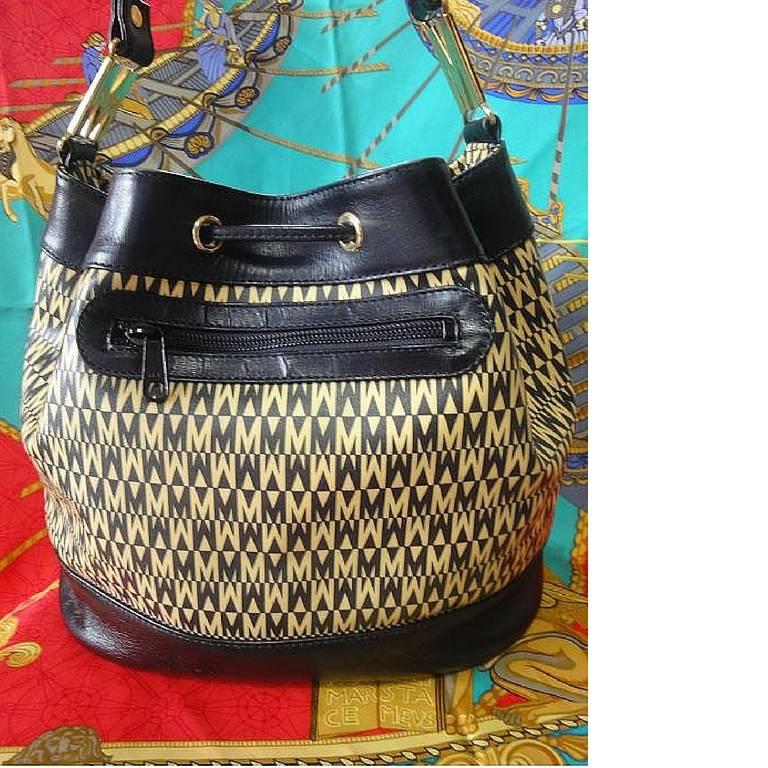 Vintage MOSCHINO black and ivory logo print hobo bucket shoulder bag with leather trimmings and golden M charms.

Introducing a chic and cute vintage piece from Moschino in the 90's!
You will love the black and ivory allover 
