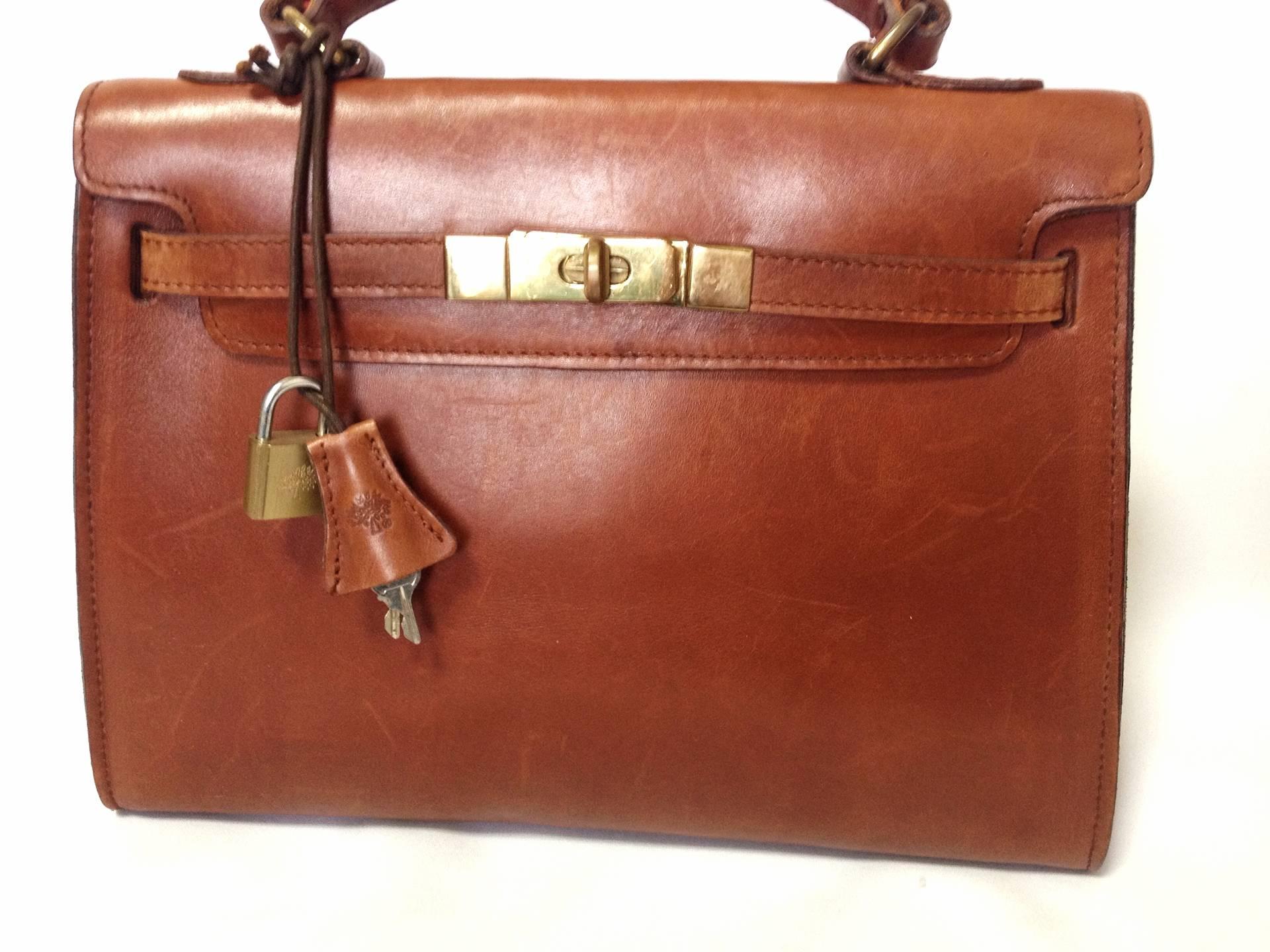 Vintage Mulberry smooth brown leather Kelly bag with keys and padlock. Roger Saul era. Rare masterpiece you must get.

Introducing another old sophisticated masterpiece from Mulberry in the Roger Saul era in the early 90s.

It has its deep