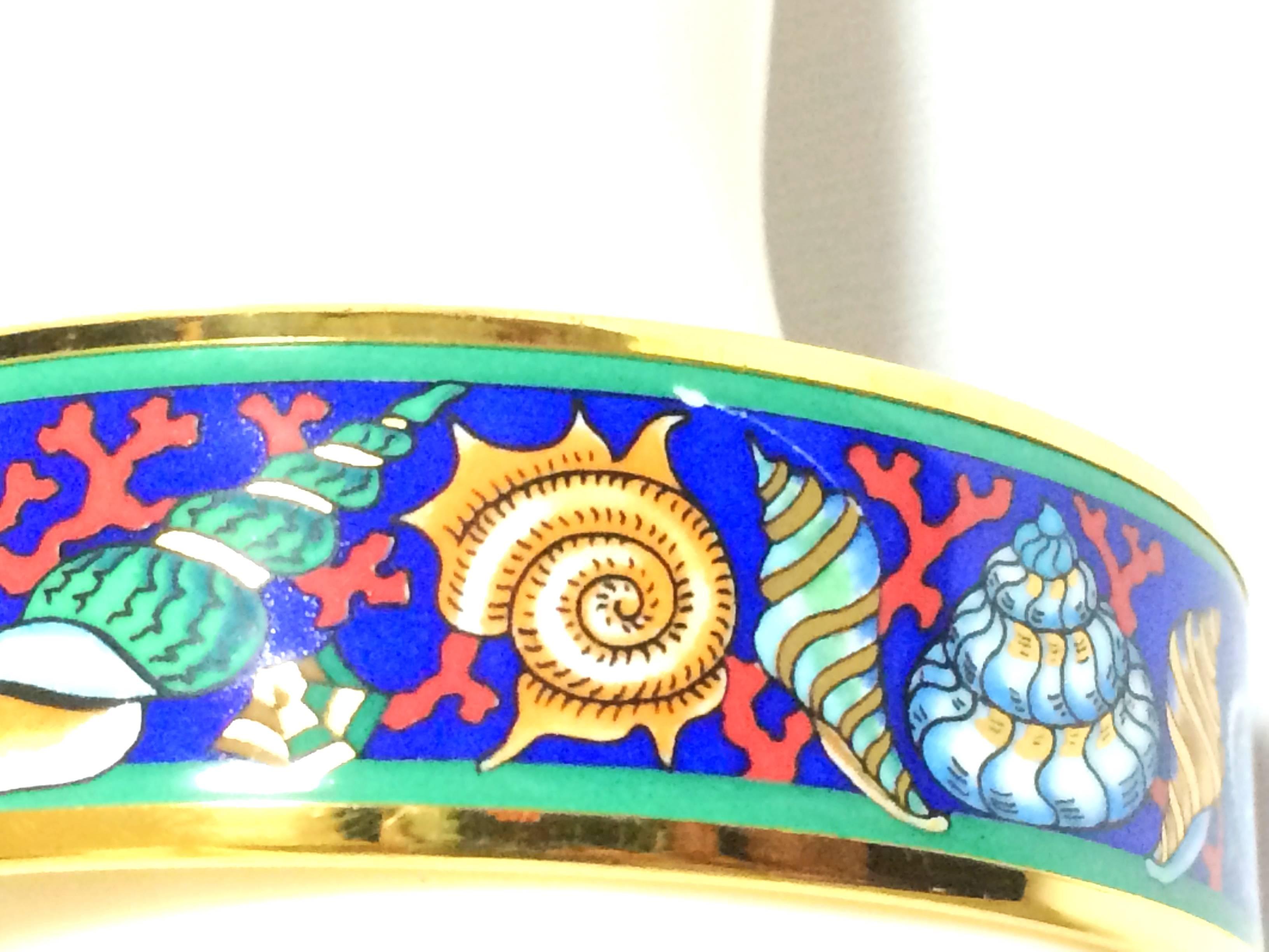 1990s. Vintage Hermes cloisonne enamel blue ocean, sea, yellow, brown, blue colorful shell, pink coral design golden thick bangle, bracelet.

Introducing a fantastic jewelry piece  from HERMES....
The iconic cloisonne enamel golden bangle!