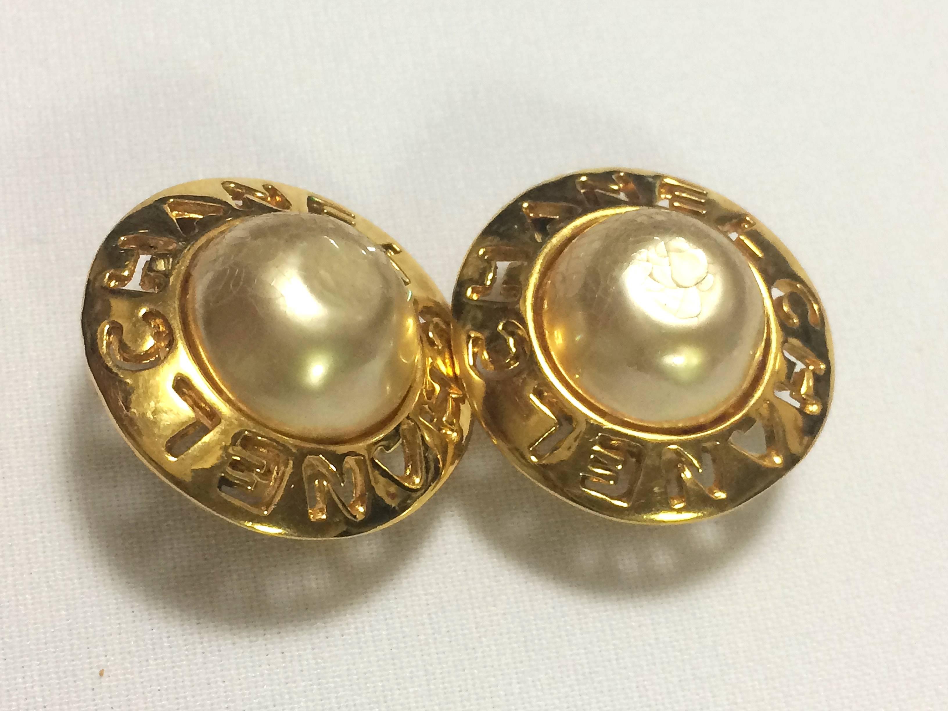 Women's Vintage CHANEL golden round shape faux pearl earrings with cutout logo. Chic.
