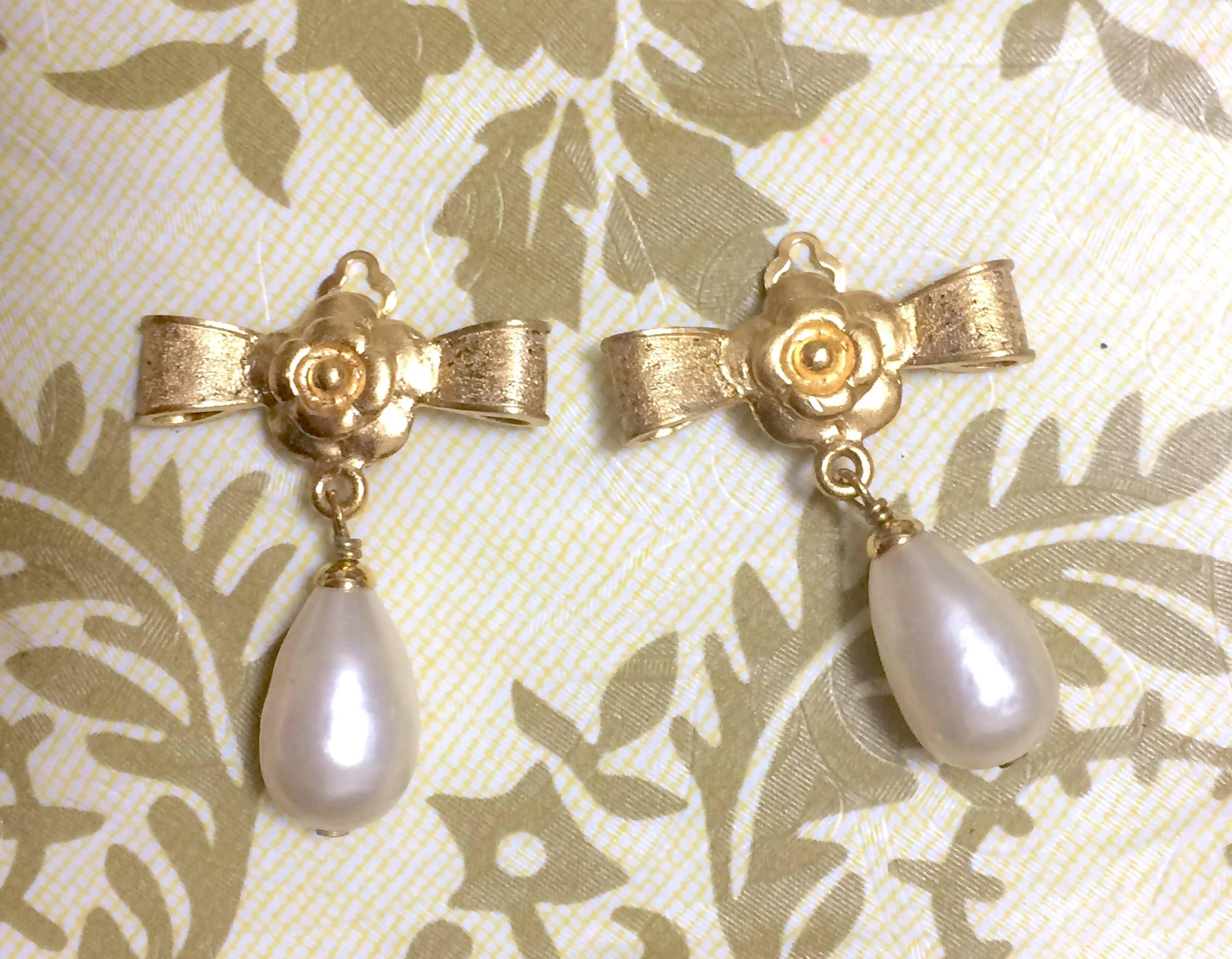 1990s. Vintage CHANEL golden bow and camellia flower design and dangling white teardrop earrings. Rare jewelry piece. Perfect gift.

Introducing another rare vintage CHANEL teardrop faux pearl earrings with golden bow and camellia motifs.

These