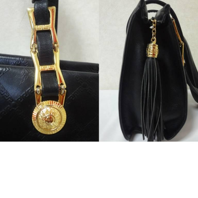 Women's Vintage Gianni Versace black leather tote bag with a tassel and sunburst motifs.