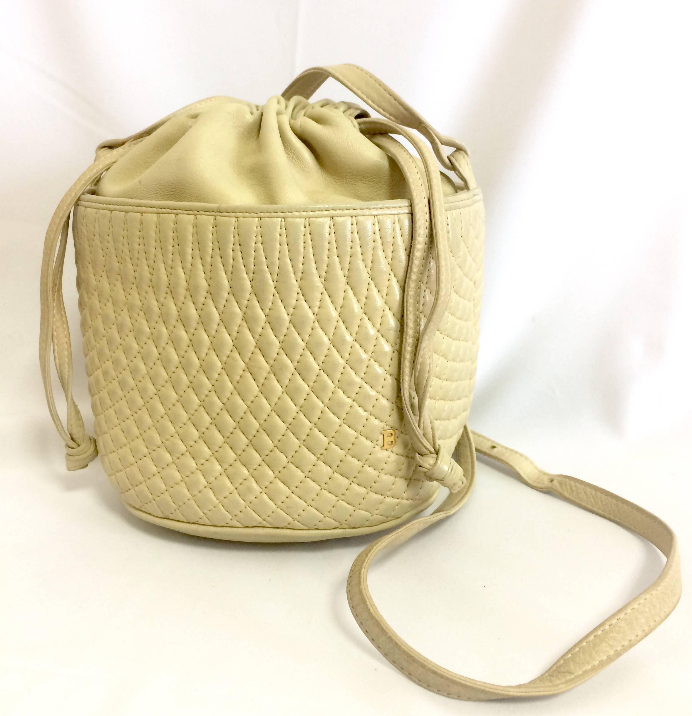 1990s. Vintage BALLY ivory white quilted lambskin mini hobo, bucket shoulder bag with golden B charm and drawstrings.

This is a vintage Bally ivory white genuine lambskin quilted leather mini hobo shoulder bag back in the old Bally collection.
It