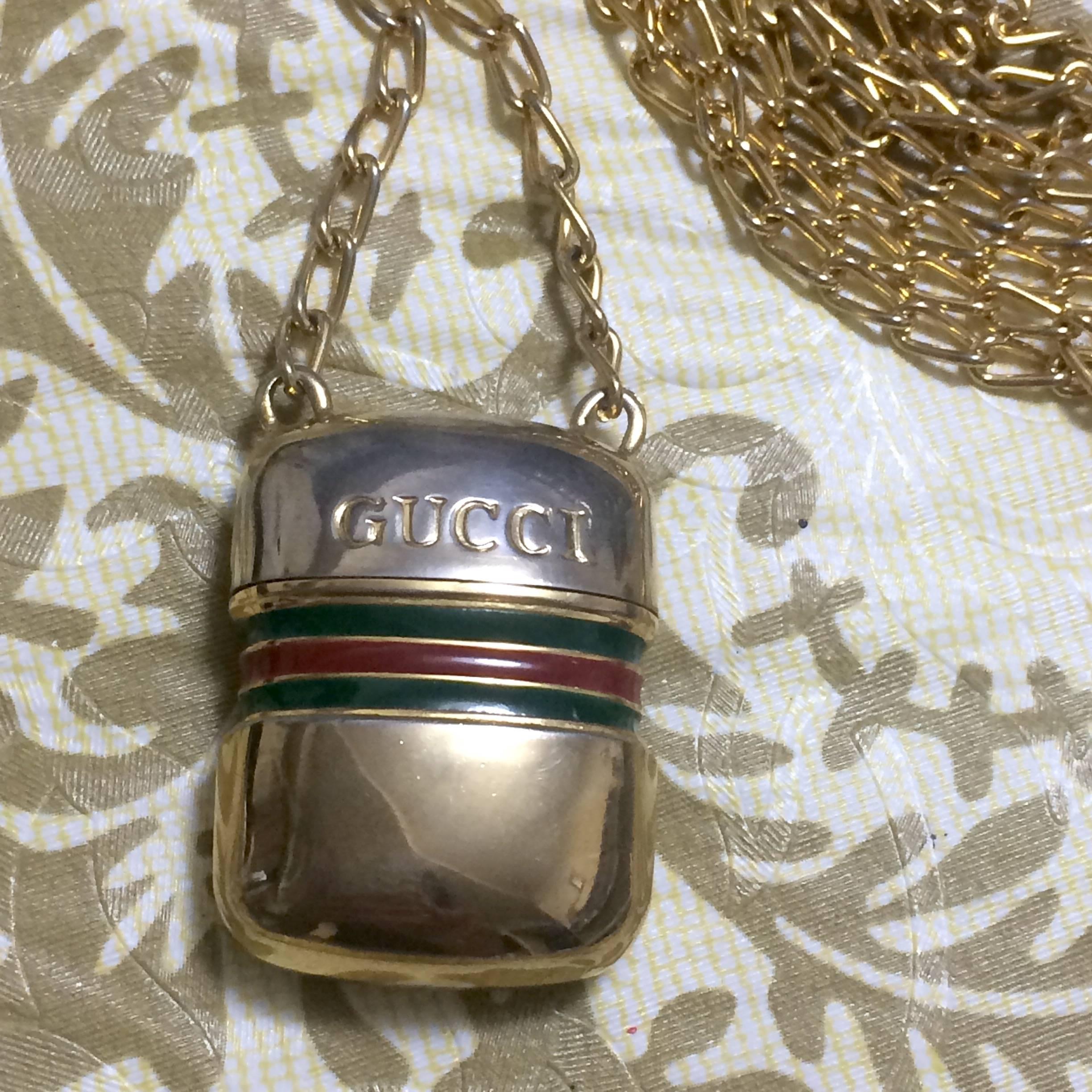 1980s. Vintage Gucci golden mini bottle, pill case design necklace with embossed logo mark and webbing sherry line motif. Gorgeous jewelry piece.

Introducing a rare vintage mini bottle necklace with the iconic green and red webbing sherry line mark