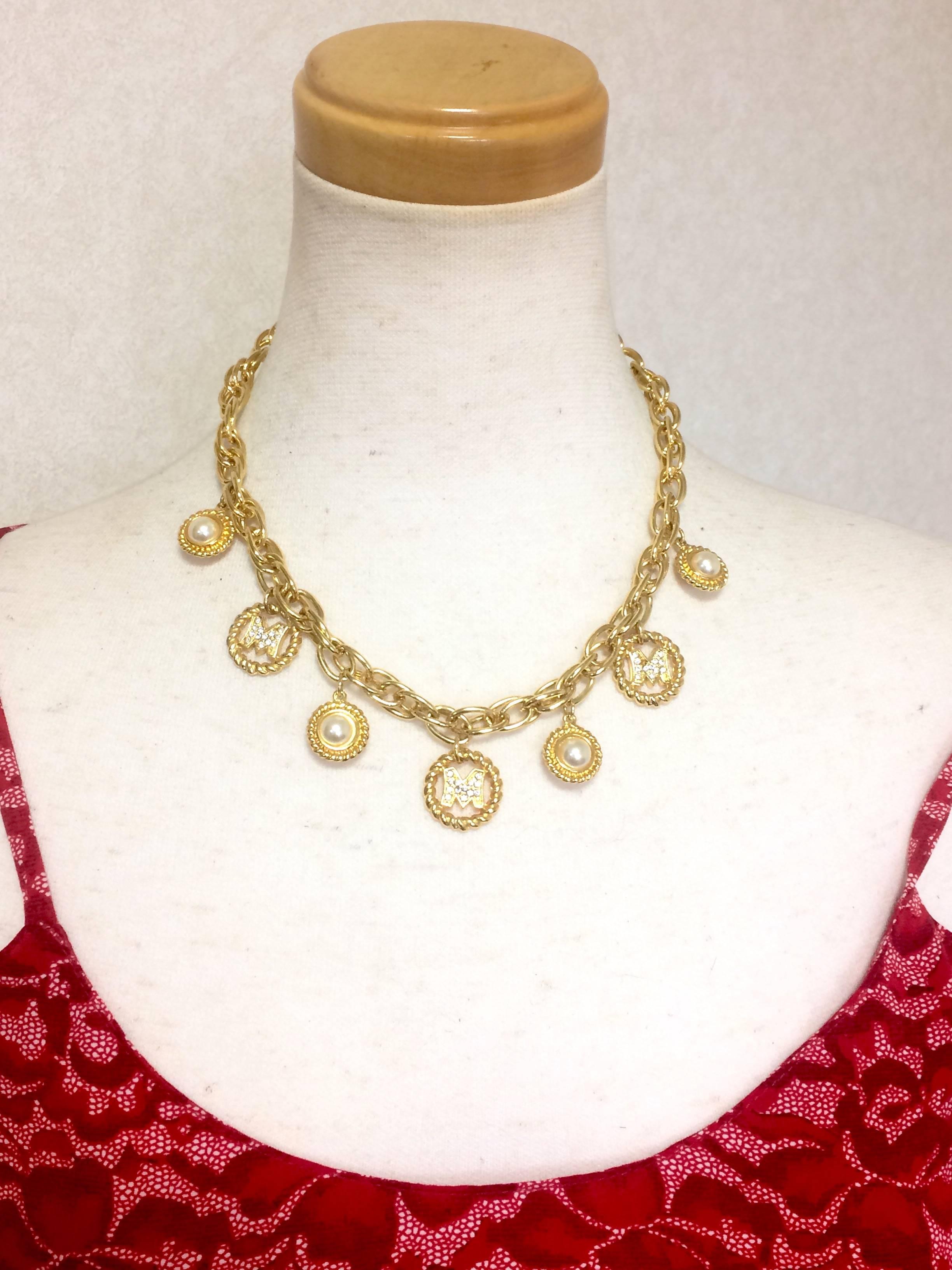 1990s. Vintage Moschino chain statement necklace with golden round dangling charms with faux pearls and letter M rhinestone motifs.

Introducing another rare and fabulous jewelry necklace from MOSCHINO back in the 90's.
It is a gorgeous chain