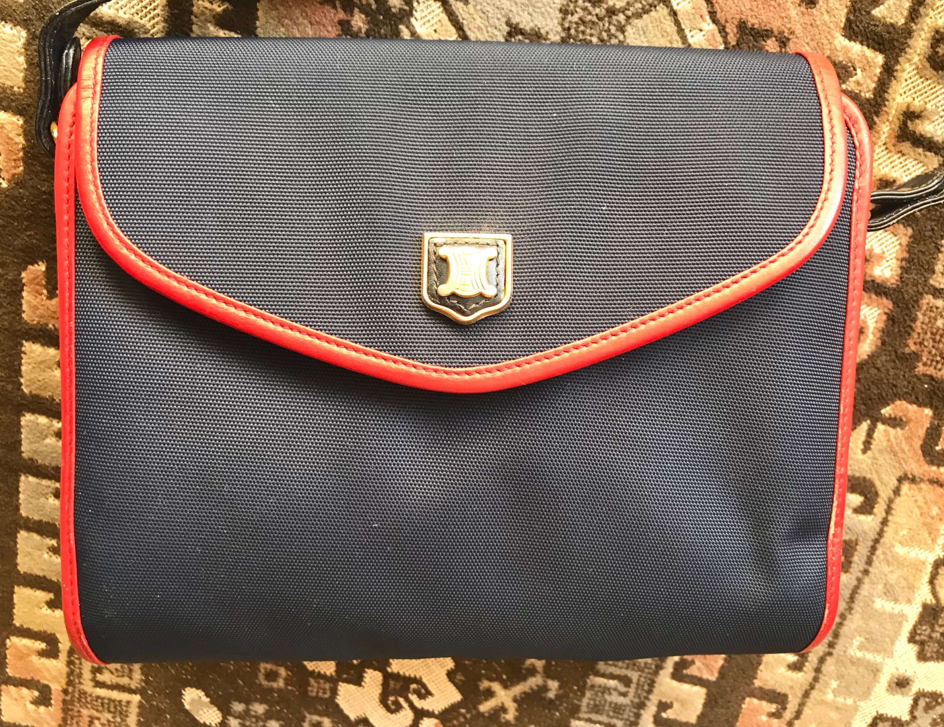 1990s. Vintage Celine navy nylon and red leather piping shoulder bag with golden blason macadam logo embossed motif on flap. riri zipper

Introducing a rare design shoulder bag from Celine back in the old era.

Featuring navy nylon fabric and red