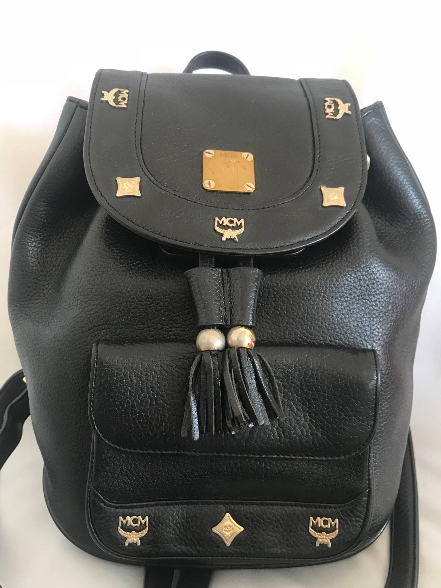 1980s. Vintage MCM black backpack with golden studded logo motifs and drawstrings. Designed by Michael Cromer. Unisex bag for daily use.

MCM has now come back in trend and so hot in the market!!

This is the vintage MCM black genuine leather