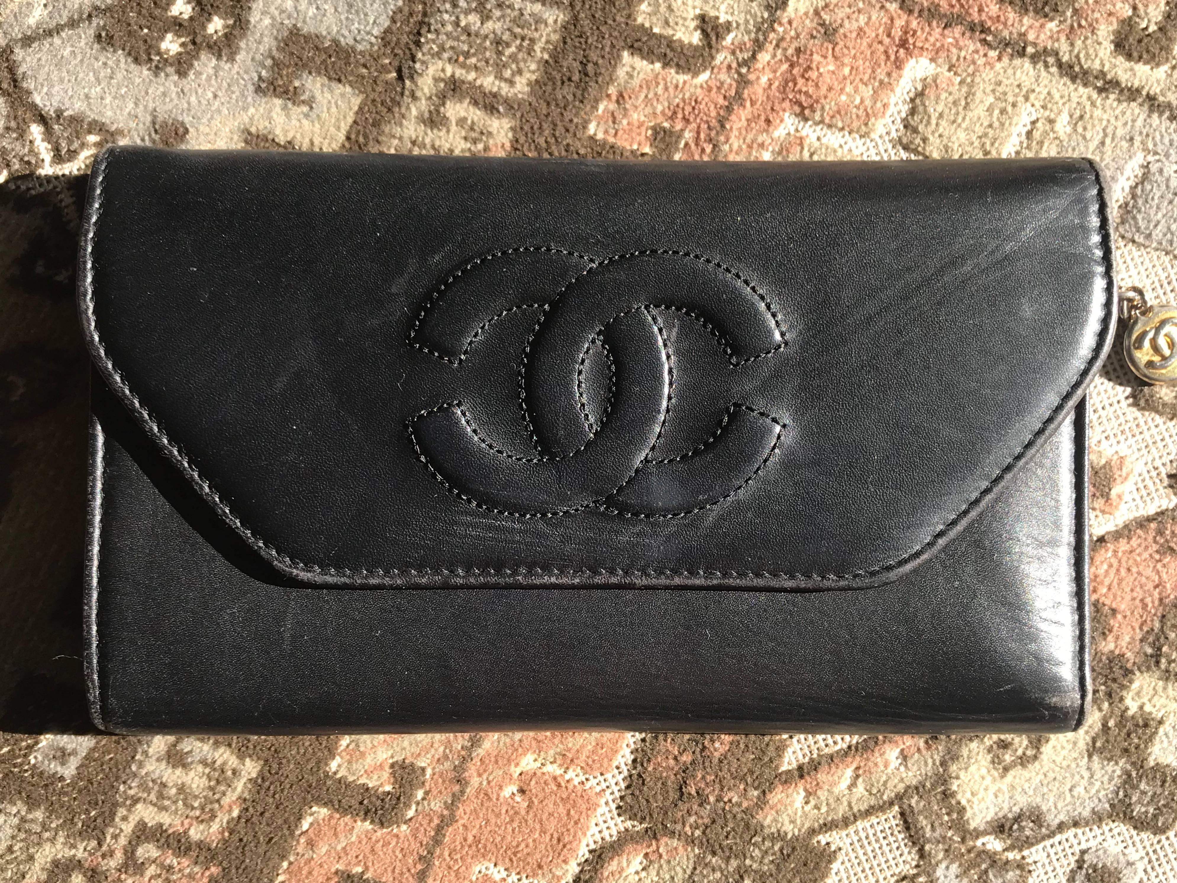 1990s. Vintage CHANEL black leather wallet with large CC stitch mark. 

This is a CHANEL vintage wallet in black calfskin from 90’s. 
Classic wallet but rare design as vintage Chanel wallets back in the 90’s;
Featuring a chain and CC mark charm to