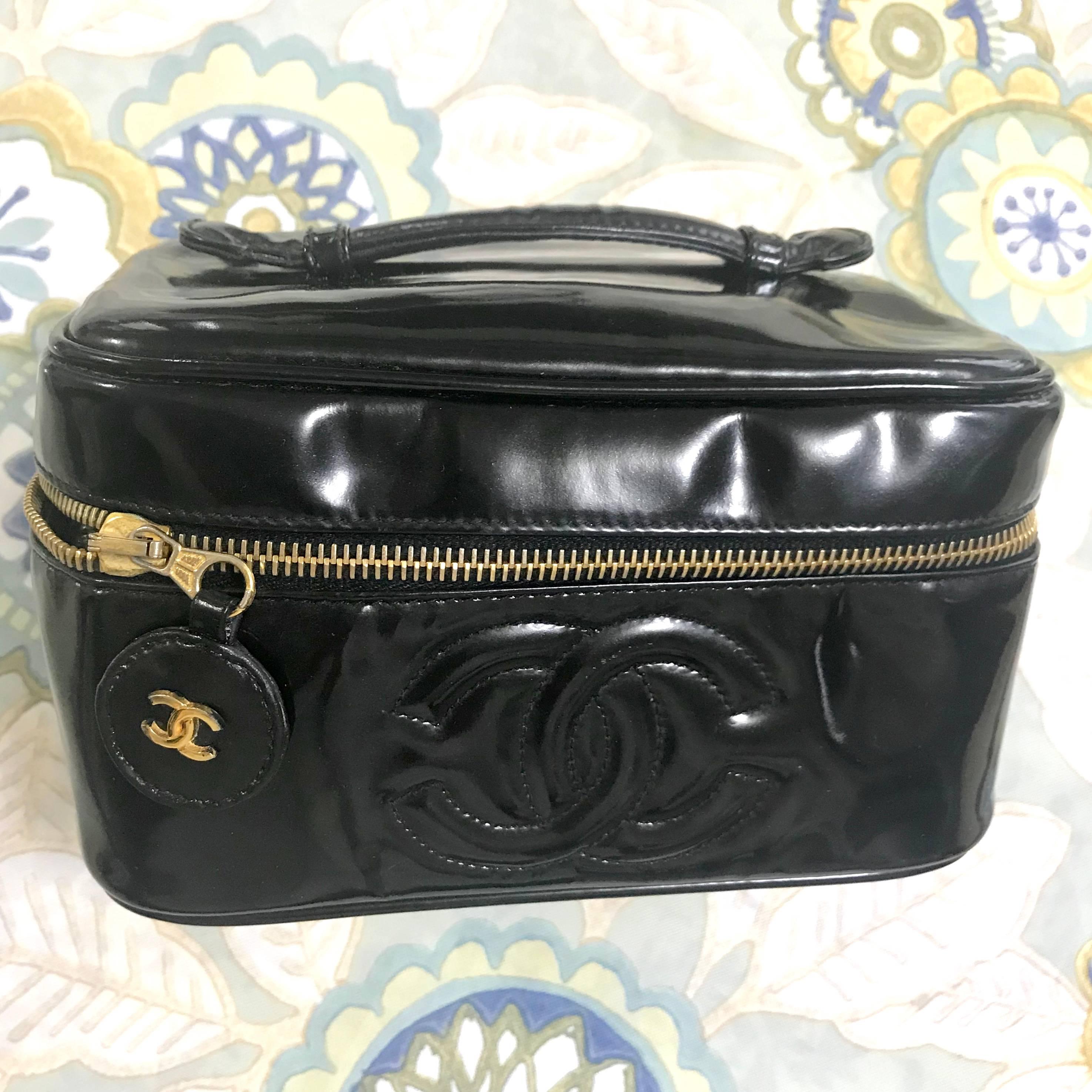 1990s. Vintage CHANEL patent enamel cosmetic and toiletry black pouch purse with CC charm. Very chic vanity purse for many use. 

This is a 90's vintage CHANEL classic black cosmetic pouch purse in black patent enamel.
Featuring a stitched CC mark