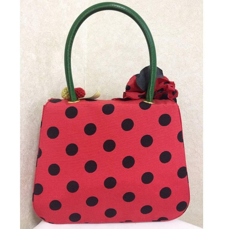 MINT Condition. Vintage MOSCHINO red and black canvas polkadot kelly handbag with a matching rose flower and leaf and crochet fruits motifs

This is a vintage, but MINT condition red and black color canvas fabric kelly purse. One-of-a-kind purse