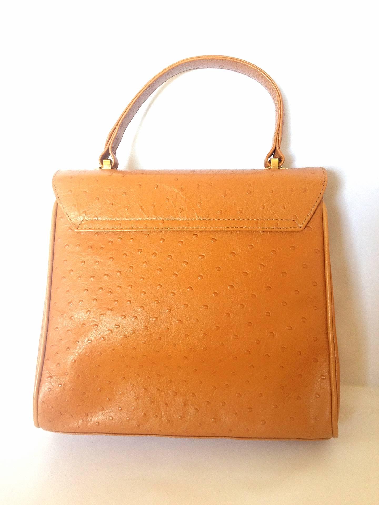 1990s. MINT. Vintage Nina Ricci tan brown ostrich-embossed leather handbag purse with golden motif at closure. Masterpiece by Maroquinerie.

Introducing a vintage Nina Ricci handbag in tanned brown leather with ostrich-embossed design.
Masterpiece