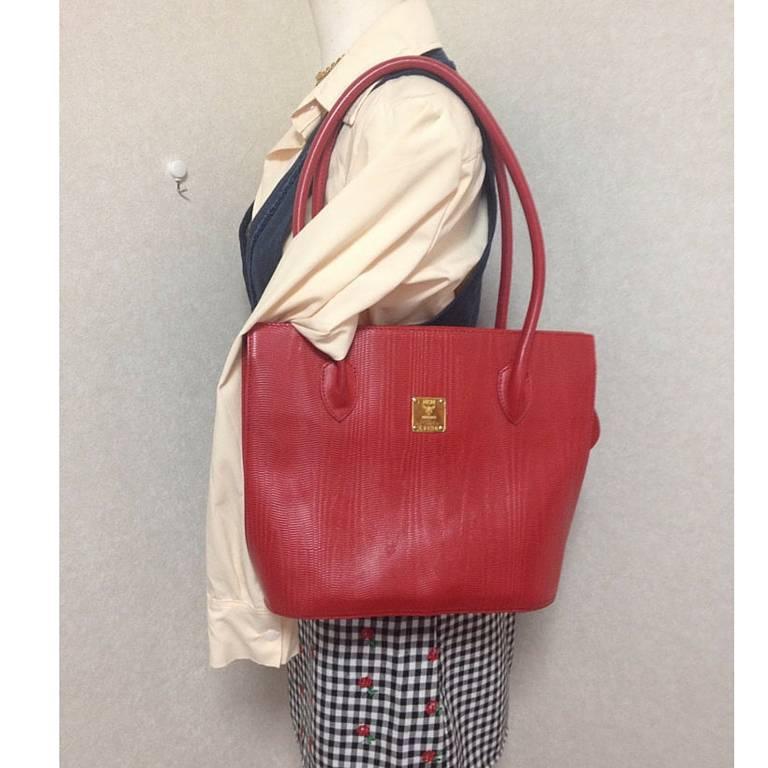 1990s. Vintage MCM red lizard embossed leather tote bag with monogram jacquard interior and golden square logo plate. Designed by Michael Cromer

MCM has been back in the fashion trend again!!
Now it's considered to be one of the must-have