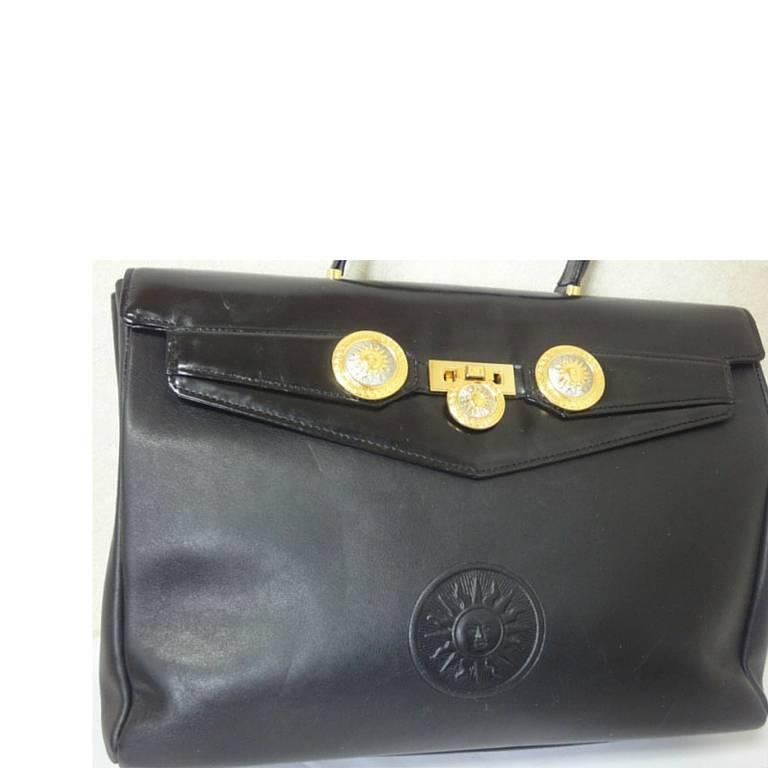 1990s. Vintage Gianni Versace genuine black leather Kelly style bag with Medallion Sunburst charms . Gorgeous masterpiece.

This is one sophisticated masterpiece from GIANNI VERSACE in the old era. 
If you are looking for vintage masterpiece from