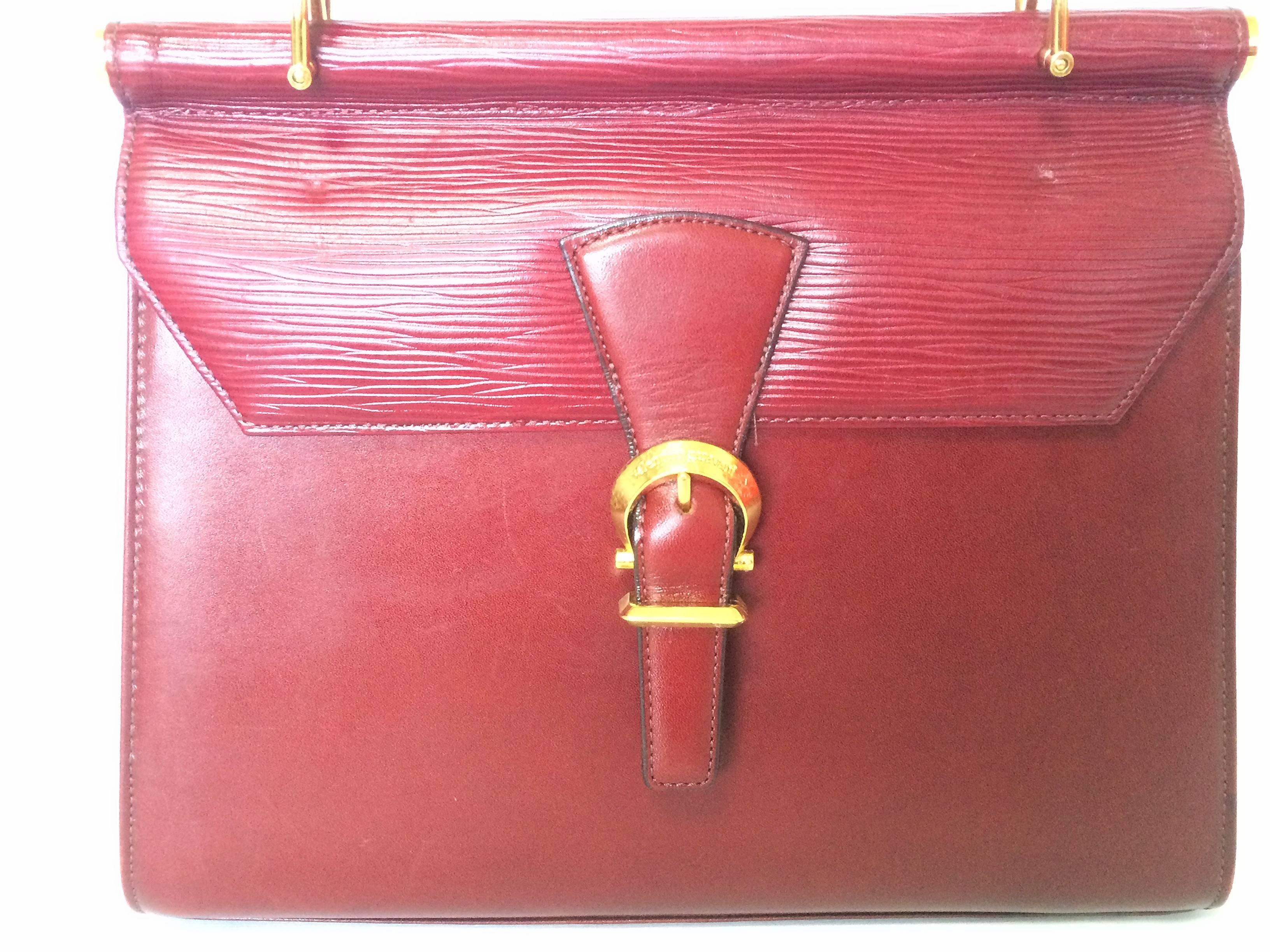 1990s. Vintage Valentino Garavani wine epi and smooth leather handbag with golden buckle design closure.Classic Valentino purse for any occasions.

This is the vintage Valentino Garavani wine/bordeaux leather purse approx early 90s.
Classic style