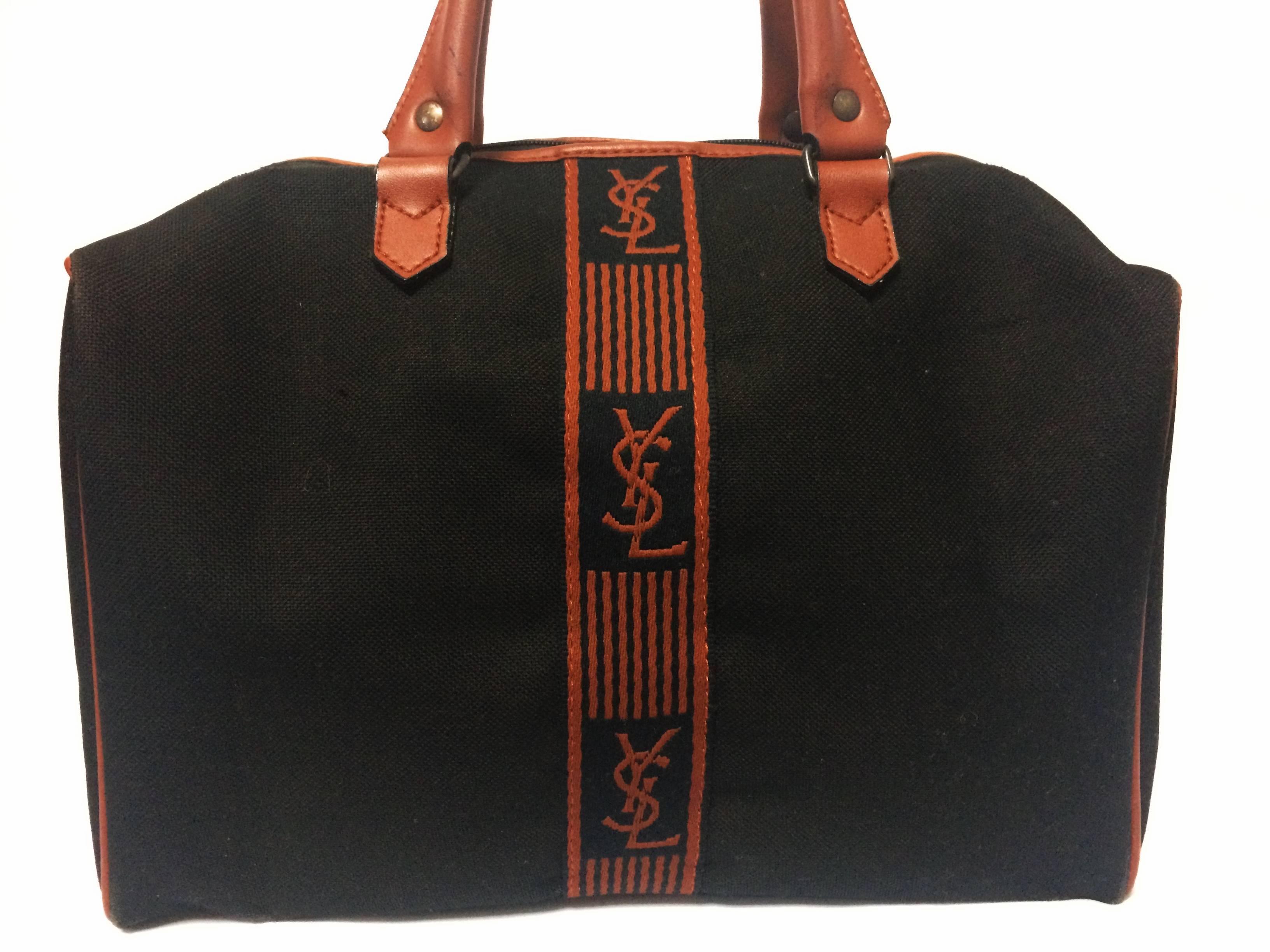1980s. Vintage Yves Saint Laurent black canvas duffle handbag, mini travel bag with brown trimmings and YSL logo. Unisex purse for daily use. 

Introducing another vintage bag for unisex use from YSL, Yves Saint Laurent back in the late 80's to