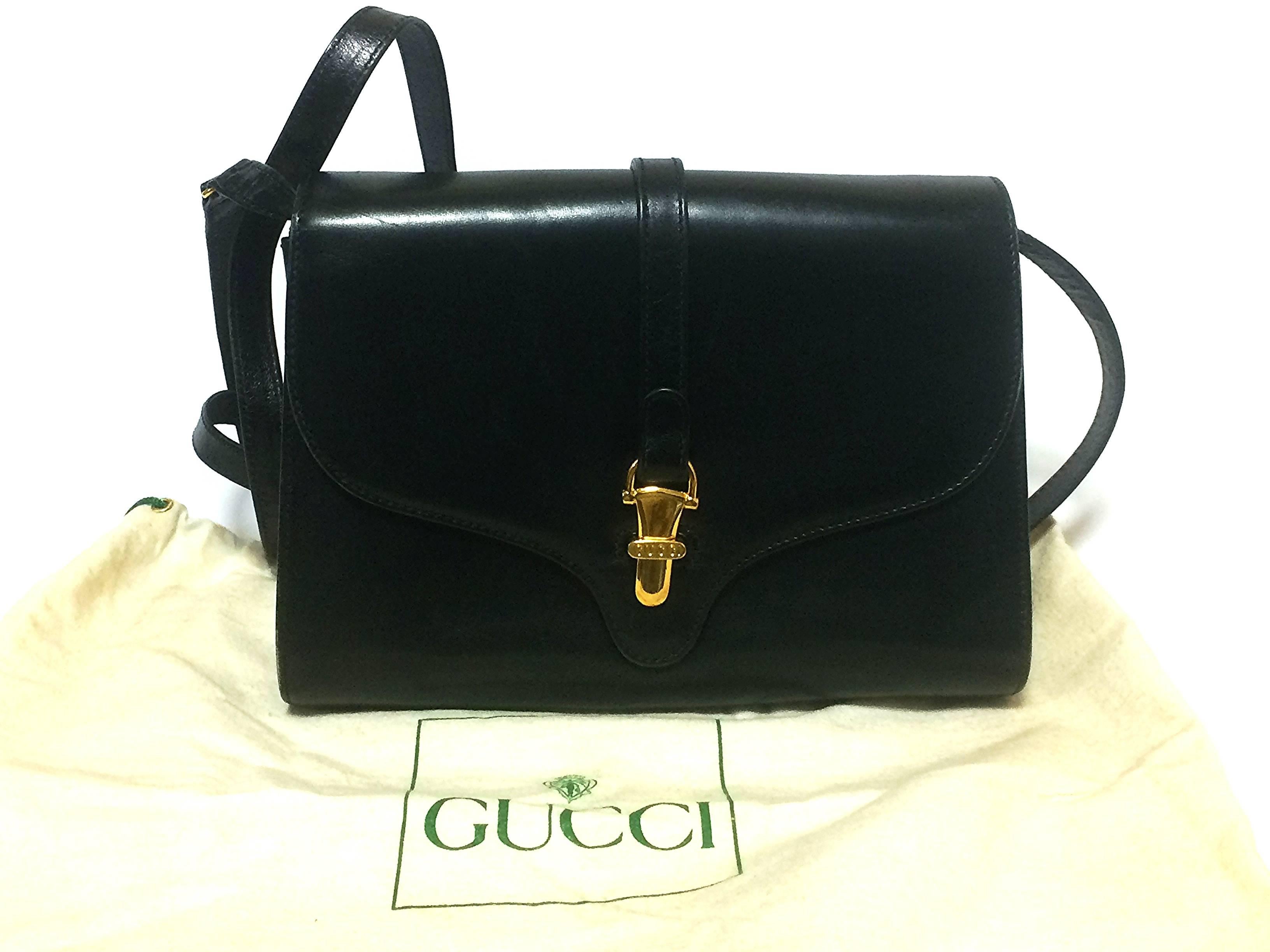 80’s Vintage Gucci black leather clutch shoulder bag with logo motif closure. 1