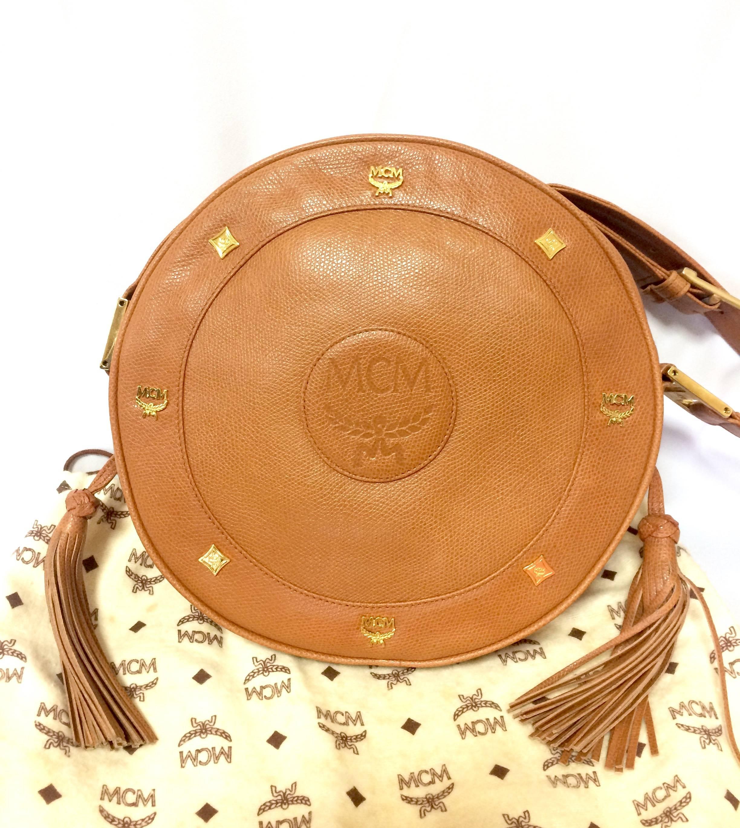 1990s. MINT. Vintage MCM brown grained leather round shoulder bag with golden logo studs and fringes. Suzy Wong shoulder bag. Unisex purse Designed by Michael Cromer.

MCM has been back in the fashion trend again!!
Now it's considered to be one of