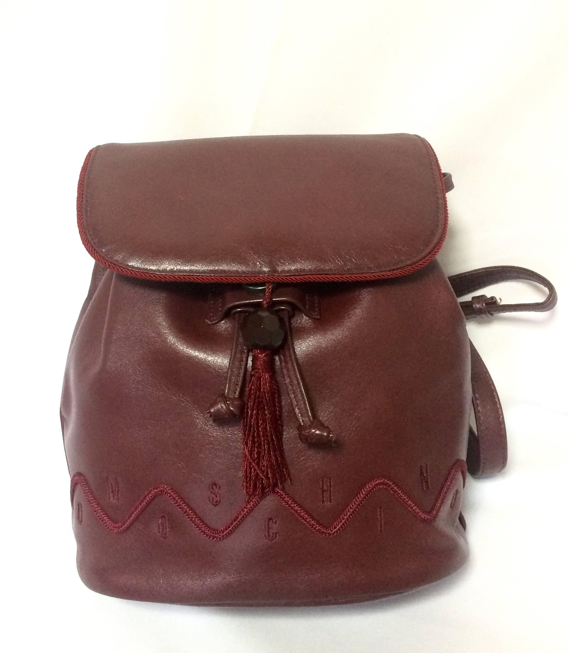 1990s. Vintage MOSCHINO genuine dark wine nappa leather backpack with tassel and logo embroidery motifs. Small to Medium size for daily use.

Introducing another unique and rare vintage piece from MOSCHINO back in the 90's.
Small to medium size
